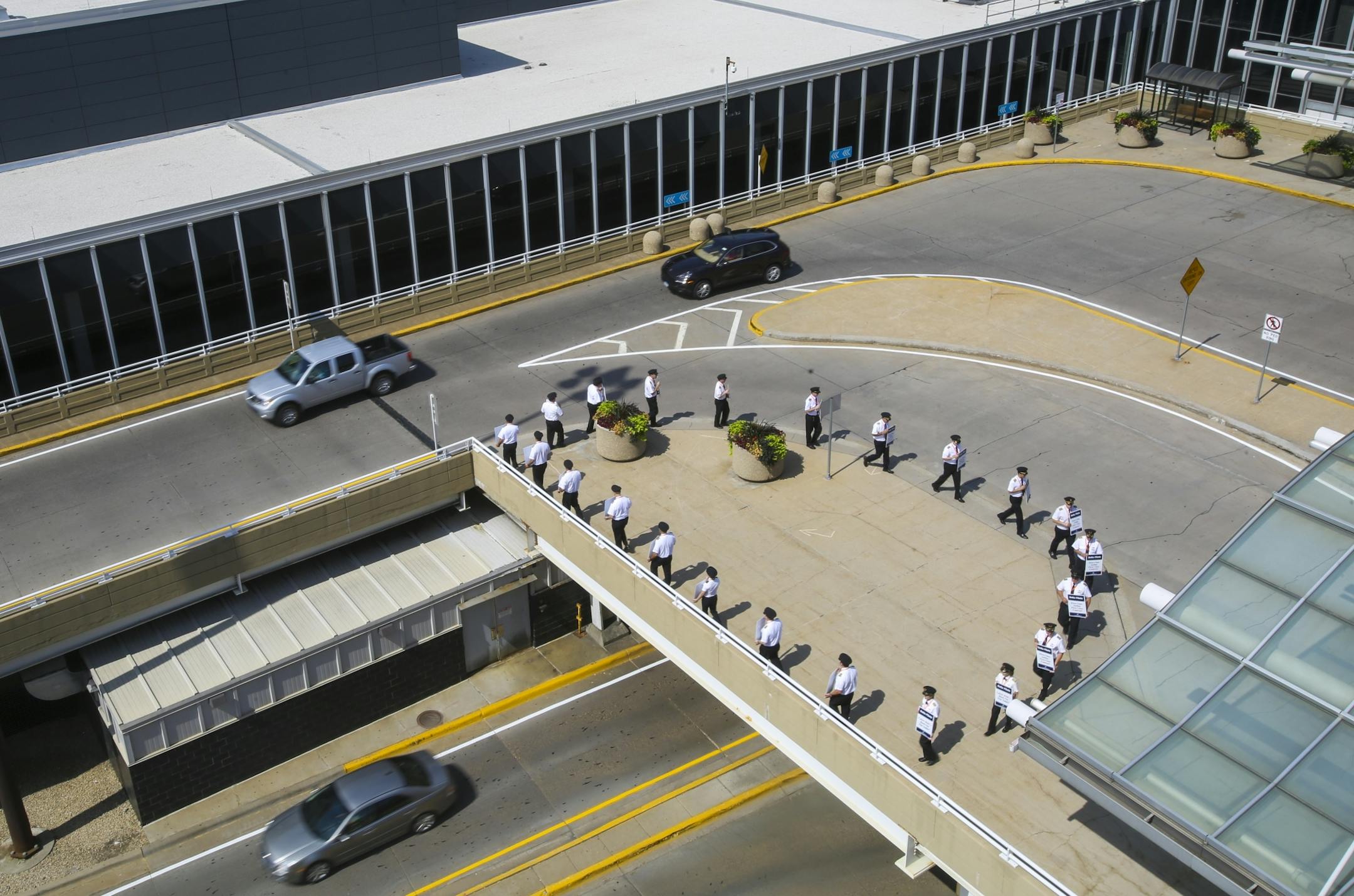 Cars pass by as picketers march around one of two designated protesting areas outside Delta Air Lines gates at terminal one. Picketers marched in these areas between one and three hours.