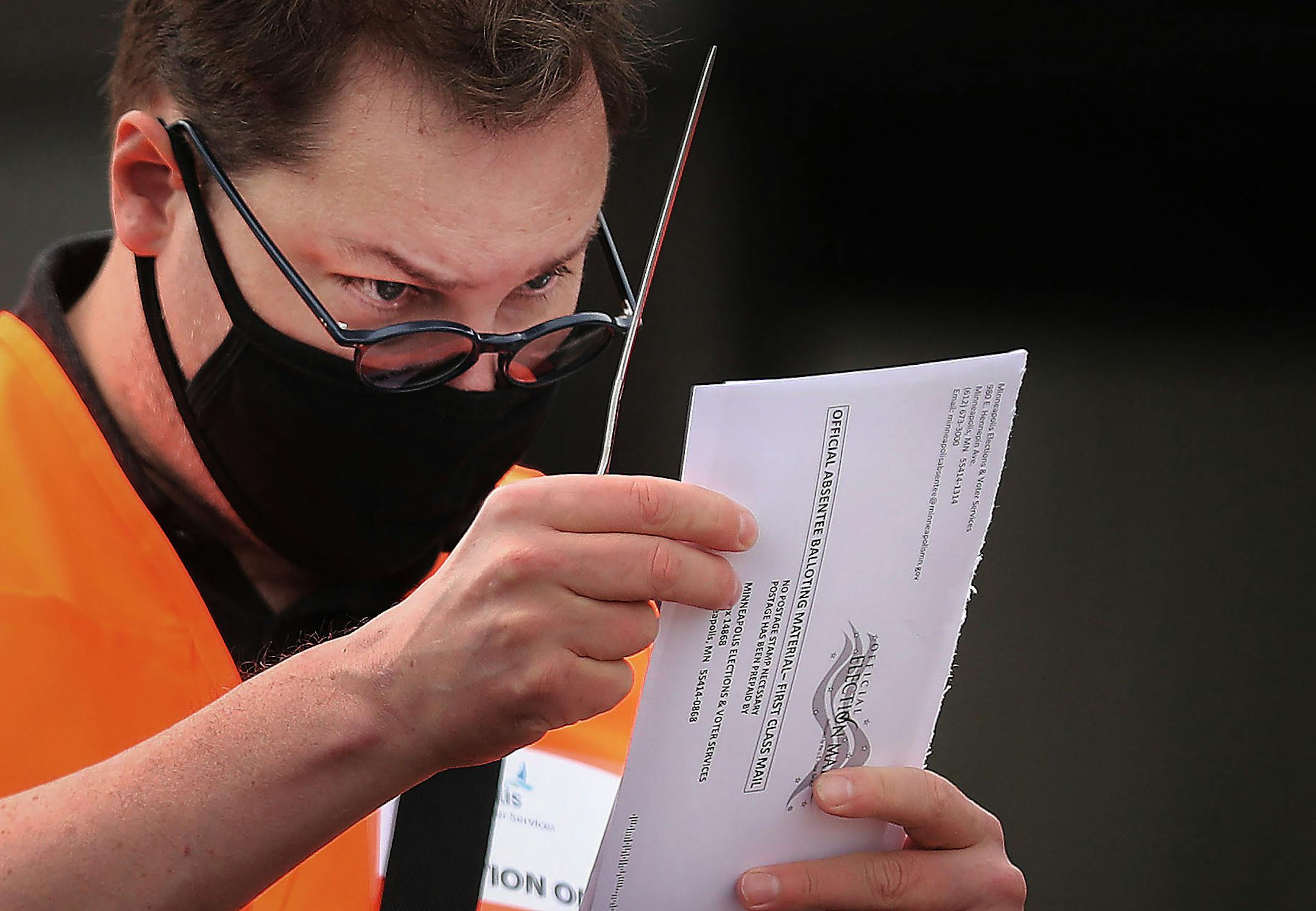 Election official Jeff Caldwell examined a primary mail-in-ballot from a motorist at Minneapolis Elections and Voter Services during a drive-through Aug. 7.