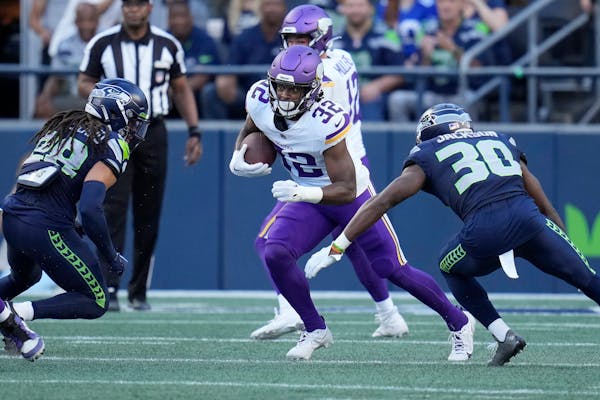 Ty Chandler (32) runs against Seattle Seahawks safety Jonathan Sutherland, left, and cornerback Michael Jackson (30) during the first half.