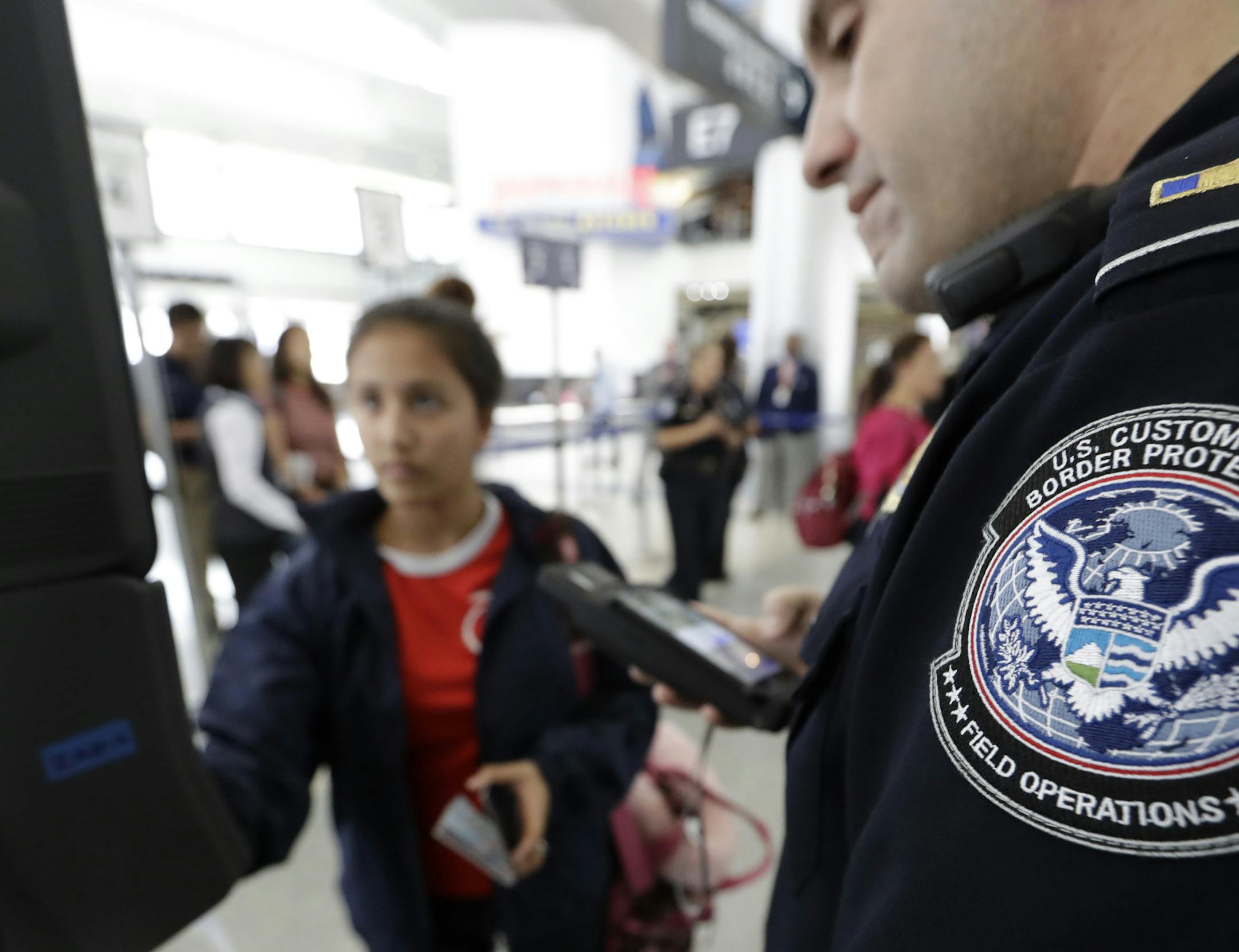 U.S. Customs and Border Protection officer Julio Corro, right, helps a passenger navigate one of the new facial recognition kiosks at a United Airlines gate before boarding a flight to Tokyo, Wednesday, July 12, 2017, at George Bush Intercontinental Airport, in Houston. The Trump administration intends to require that American citizens boarding international flights submit to face scans, something Congress has not explicitly approved and privacy advocates consider an ill-advised step toward a su