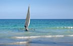 Crew members push a traditional fishing boat called a ngalawa, or catamaran, out from shore into the Indian Ocean near Diani, Kenya.