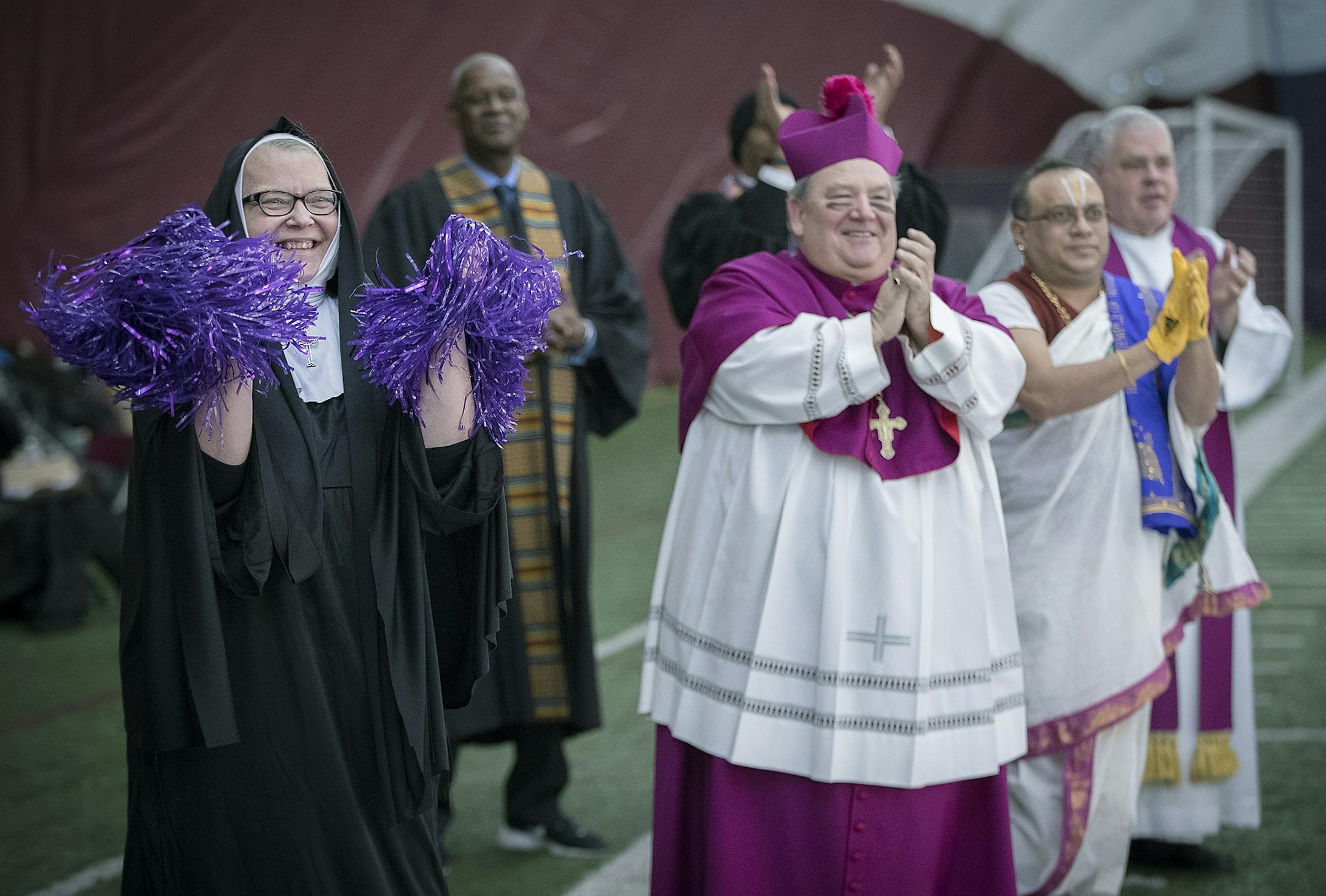 Local religious leaders, including Archbishop Bernard Hebda, center, cheered on those that were throwing a football for the filming of a commercial featuring about 30 religious leaders to benefit the Downtown Congregations to End Homelessness in the Augsburg Sports Dome, Friday, January 12, 2018 in Minneapolis, MN. The Super Bowl Host Committee planned to the commercial to benefit the Downtown Congregations to End Homelessness.