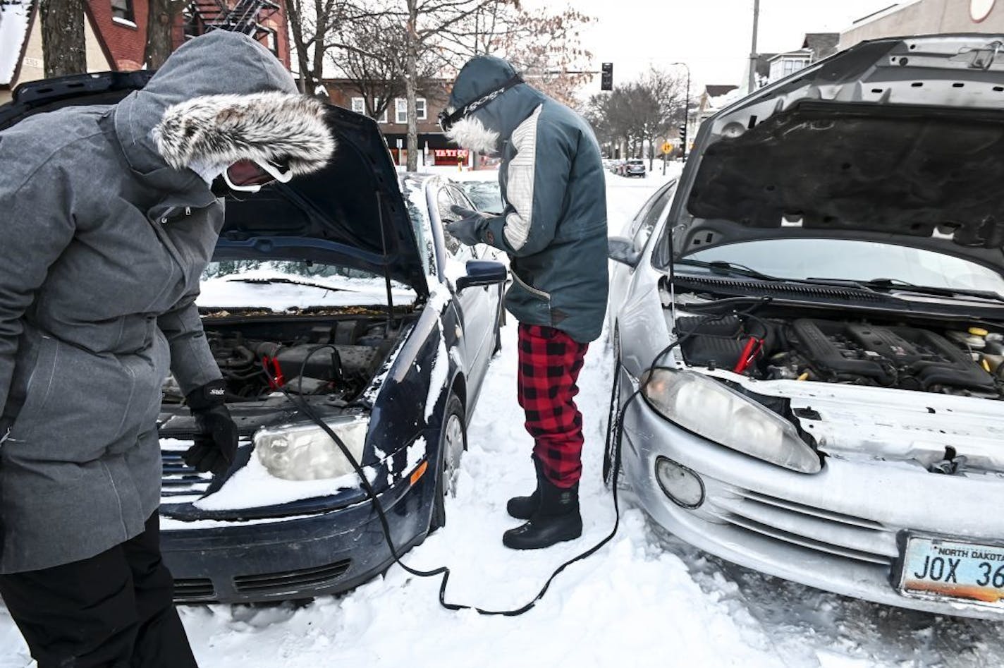 Amy Disselkamp, left, got a helping hand from friend Christian Calabrese with jumping her car off of Hennepin Avenue on Tuesday.