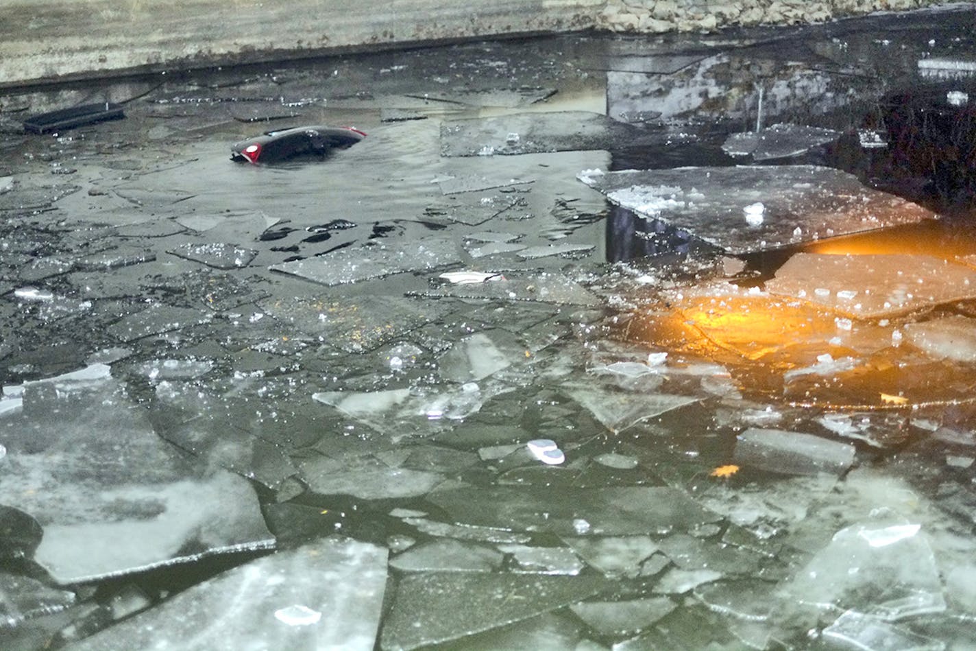 Lights from a submerged vehicle under a bridge across a lake Minnetonka channel. The car went through the ice with 4 people inside.