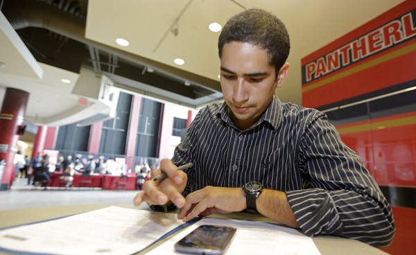 In this photo taken Tuesday, Aug. 19, 2014, Freddy Jerez, of Hollywood, Fla., fills out a job application during a job fair in Sunrise. Fla. The gover