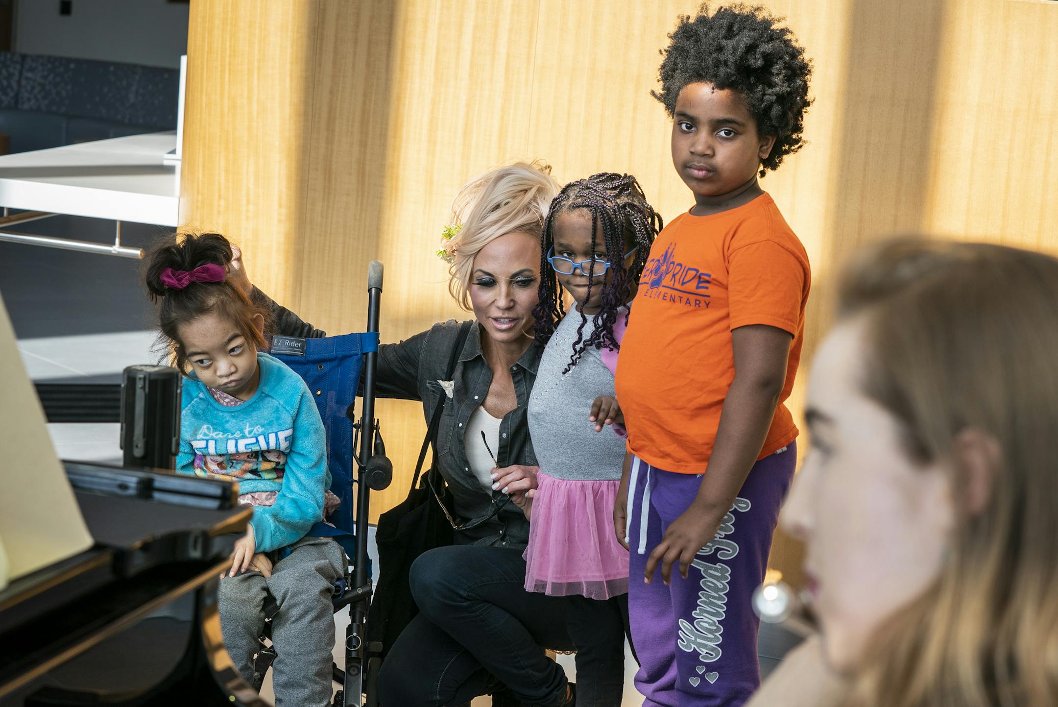 Tara Canfield, second from left, watches with her children from left, Tori, Ruby and Tuesday as Megan Reich performs on the flute in the lobby of the University of Minnesota Health Clinics and Surgery Center. Canfield was taking her daughter Tori to an appointment and stopped to enjoy the music.