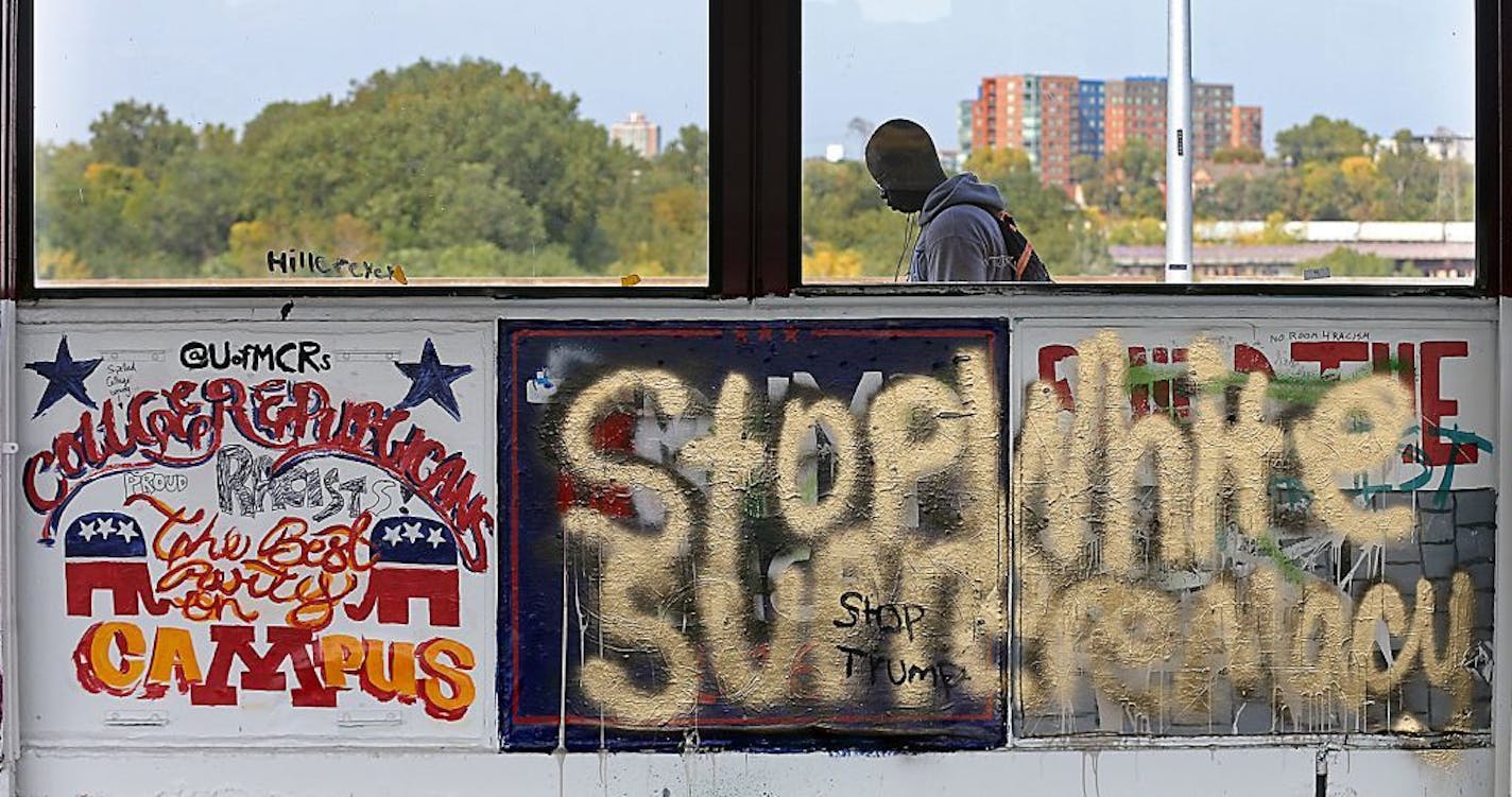 A U of M student made his way across the Washington Avenue Bridge seemingly unaware of the graffiti that is rousing controversy over a "build the wall" message that university college Republicans painted on the bridge, and others painted over, Tuesday, October 4, 2016 in Minneapolis, MN.