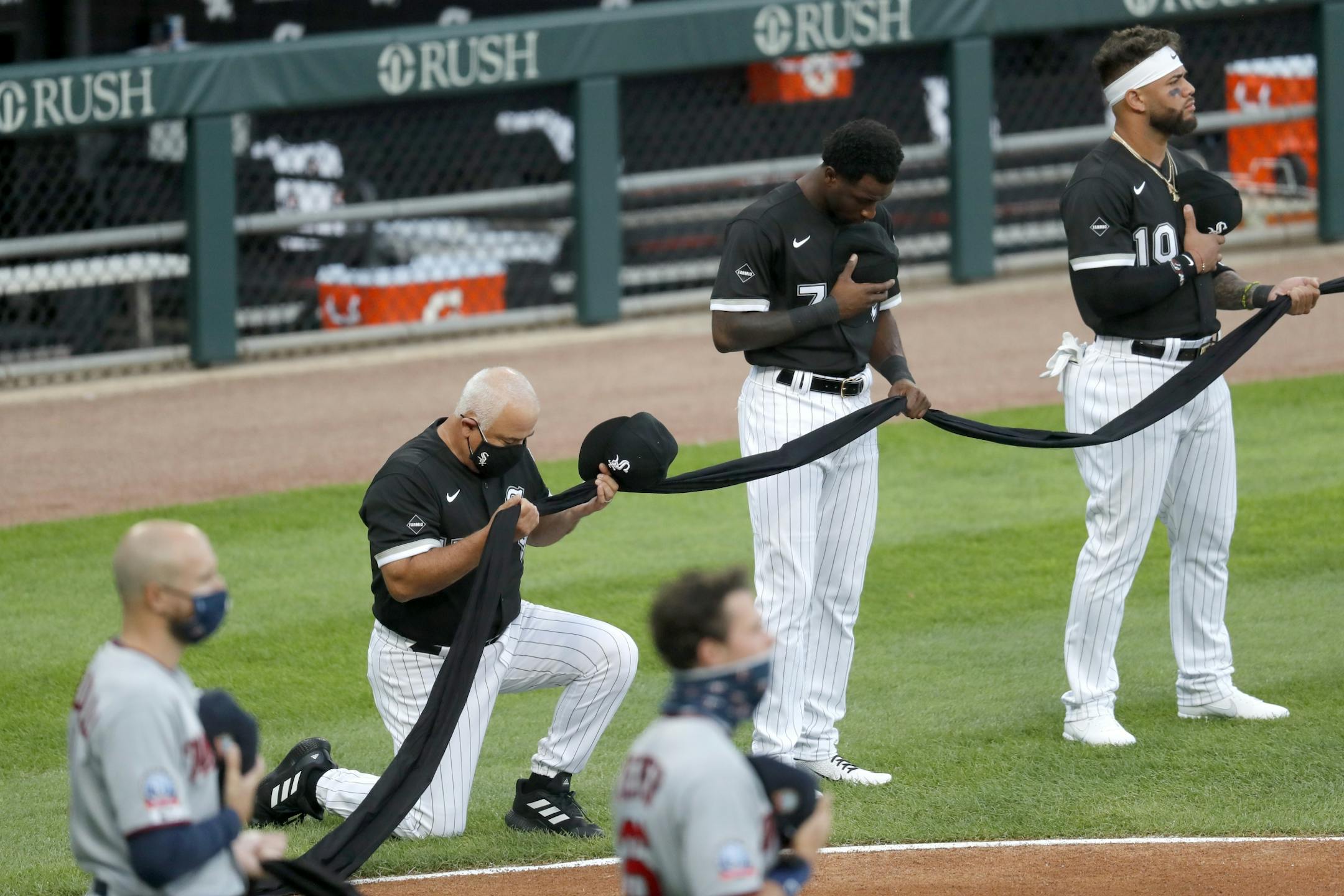Chicago White Sox manager Ricky Renteria kneels for social justice next to Tim Anderson (7) and Yoan Moncada before a baseball game against the Minnesota Twins, Friday, July 24, 2020, in Chicago.