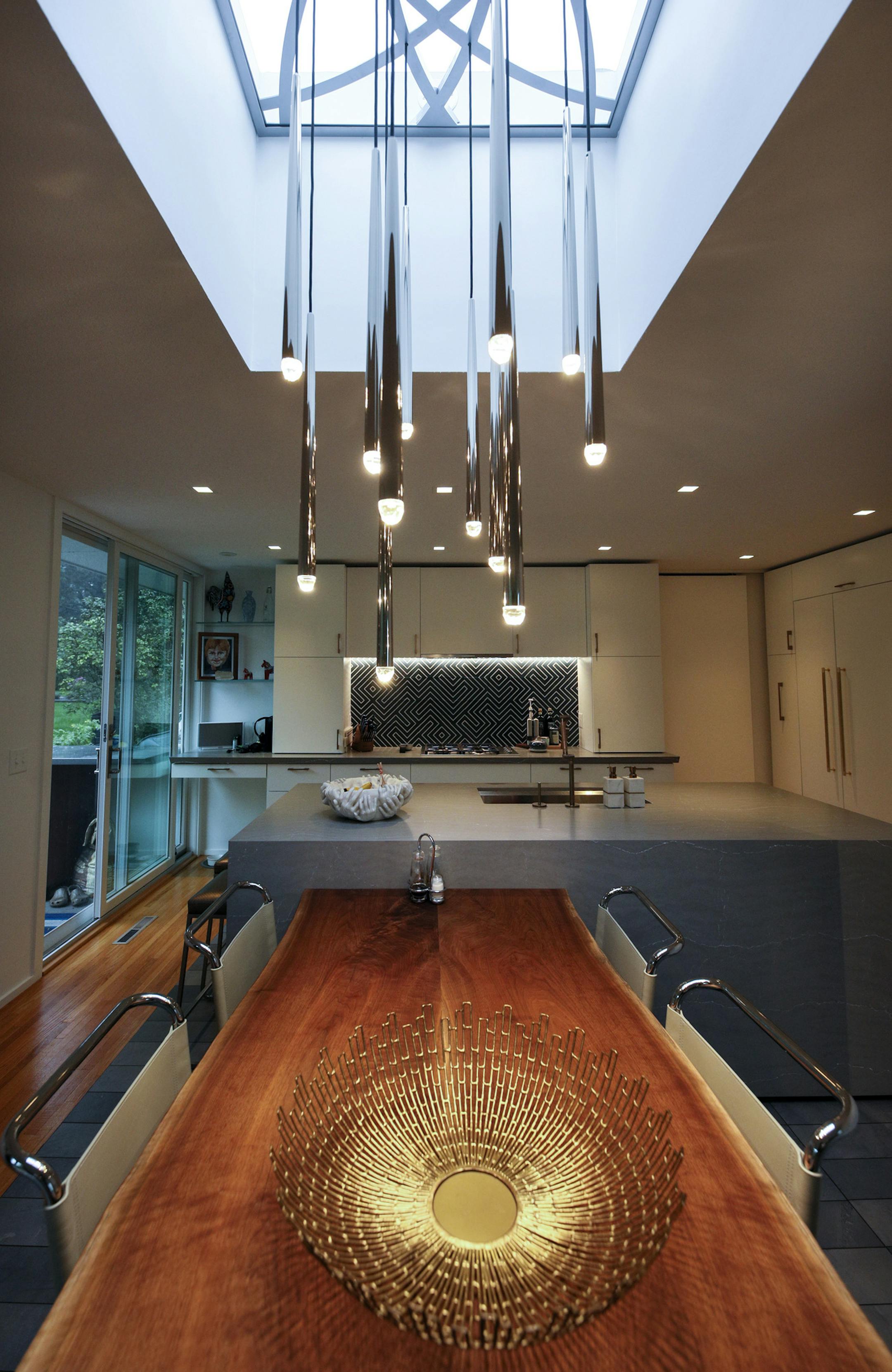 Matt Muenster of TV's "Bath Crashers" and his wife, Kate Walthour, above, in their midcentury modern home, designed by Ralph Rapson, in the University Grove neighborhood of Falcon Heights. Muenster's updates to the home include a new kitchen, top, featuring a walnut-topped dining table and lighting suspended from a grid that Muenster designed to fit into the skylight.