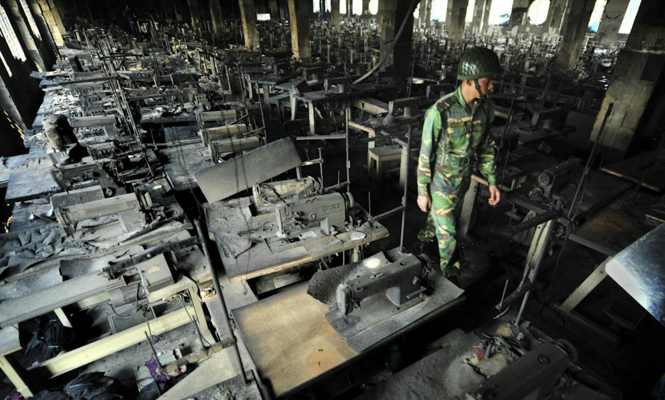 A Bangladeshi police officer walks between rows of burnt sewing machines in a garment factory outside Dhaka, Bangladesh, Sunday, Nov. 25, 2012. At least 112 people were killed in a late Saturday night fire that raced through the multi-story garment factory just outside of Bangladesh's capital, an official said Sunday.