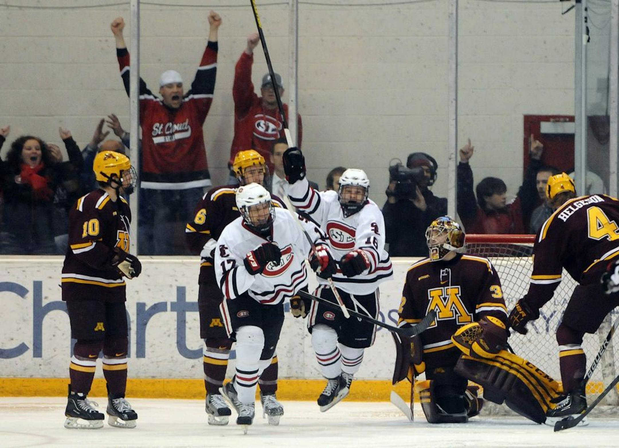 St. Cloud State's Joey Holka (17) and Garrett Milan (18) celebrate Holka's goal against Minnesota goaltender Adam Wilcox.