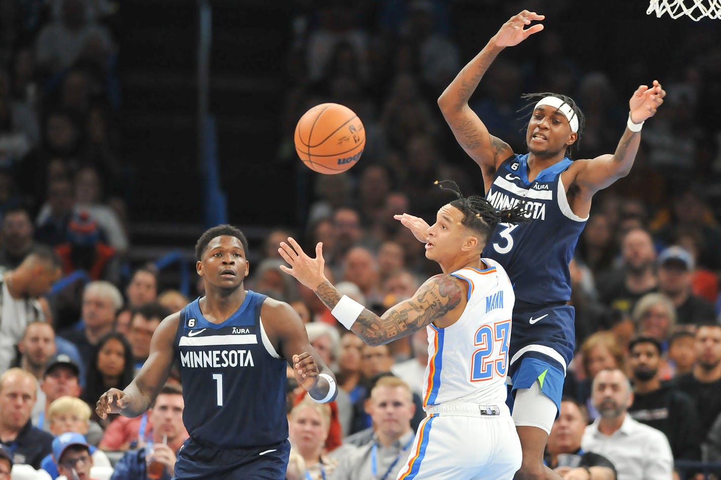 Oklahoma City Thunder guard Tre Mann (23) tries to keep the ball away from Minnesota Timberwolves forwards Anthony Edwards (1) and Jaden McDaniels (3) in the second half of an NBA basketball game, Sunday, Oct. 23, 2022, in Oklahoma City. (AP Photo/Kyle Phillips)