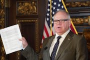 Gov. Tim Walz held up a supplemental budget at a news conference in 2020.