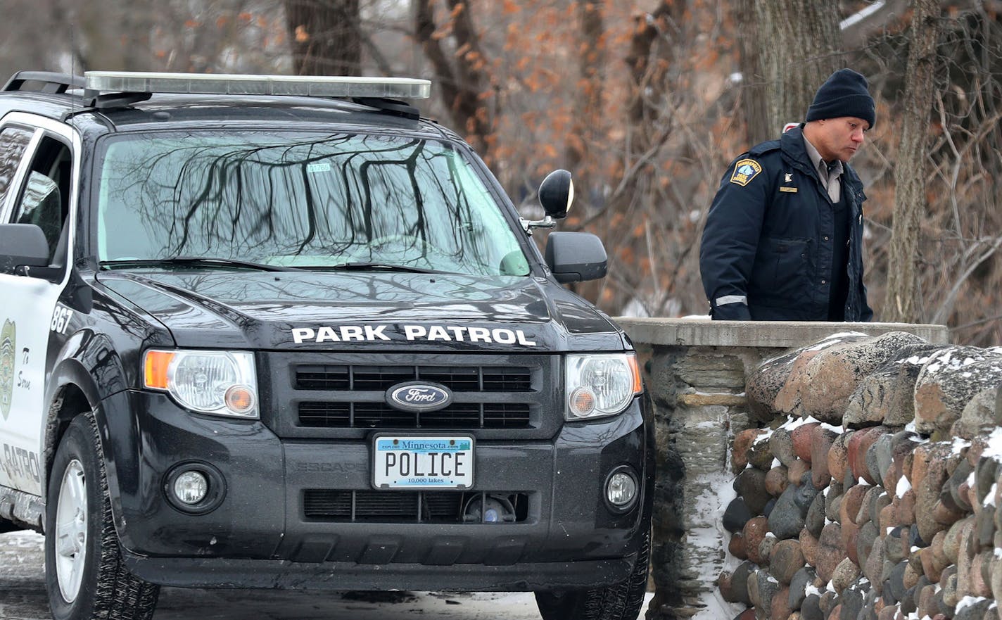 A Minneapolis Park Police officer monitors people below near the frozen waters beneath Minnehaha Falls Tuesday, Jan. 2, 2018, in Minneapolis, MN. On several occasions the officer had to yell to people below to get off of the frozen falls. Thrill seekers are skirting signs and police to get onto the frozen falls and creek for selfies and the chance to explore. While the waters are mostly frozen, the moving creek flows under their feet and if one were to break through the ice it could mean certain