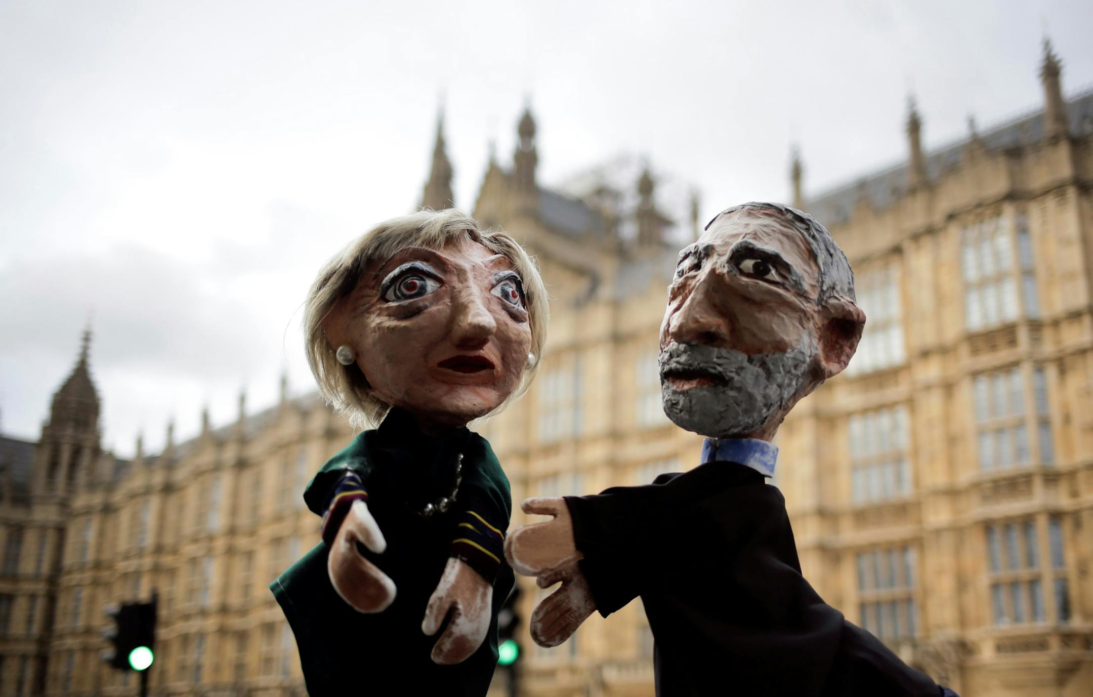 Two anti-Brexit activists pose with their hand-puppets depicting British Prime Minister and leader of the Conservative party Theresa May, left, and Britain's Labour party leader Jeremy Corbyn, during a protest, in front of the the Houses of Parliament on election day in London, Thursday, June 8, 2017. Britain voted Thursday in an election that started out as an attempt by Prime Minister Theresa May to increase her party's majority in Parliament ahead of Brexit negotiations but was upended by ter