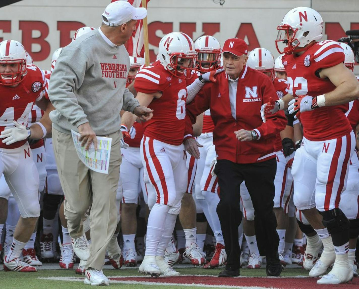 Nebraska's retiring athletic director and former head coach Tom Osborne is flanked by Tim Marlowe (6) and Rex Burkhead (22) and head coach Bo Pelini.