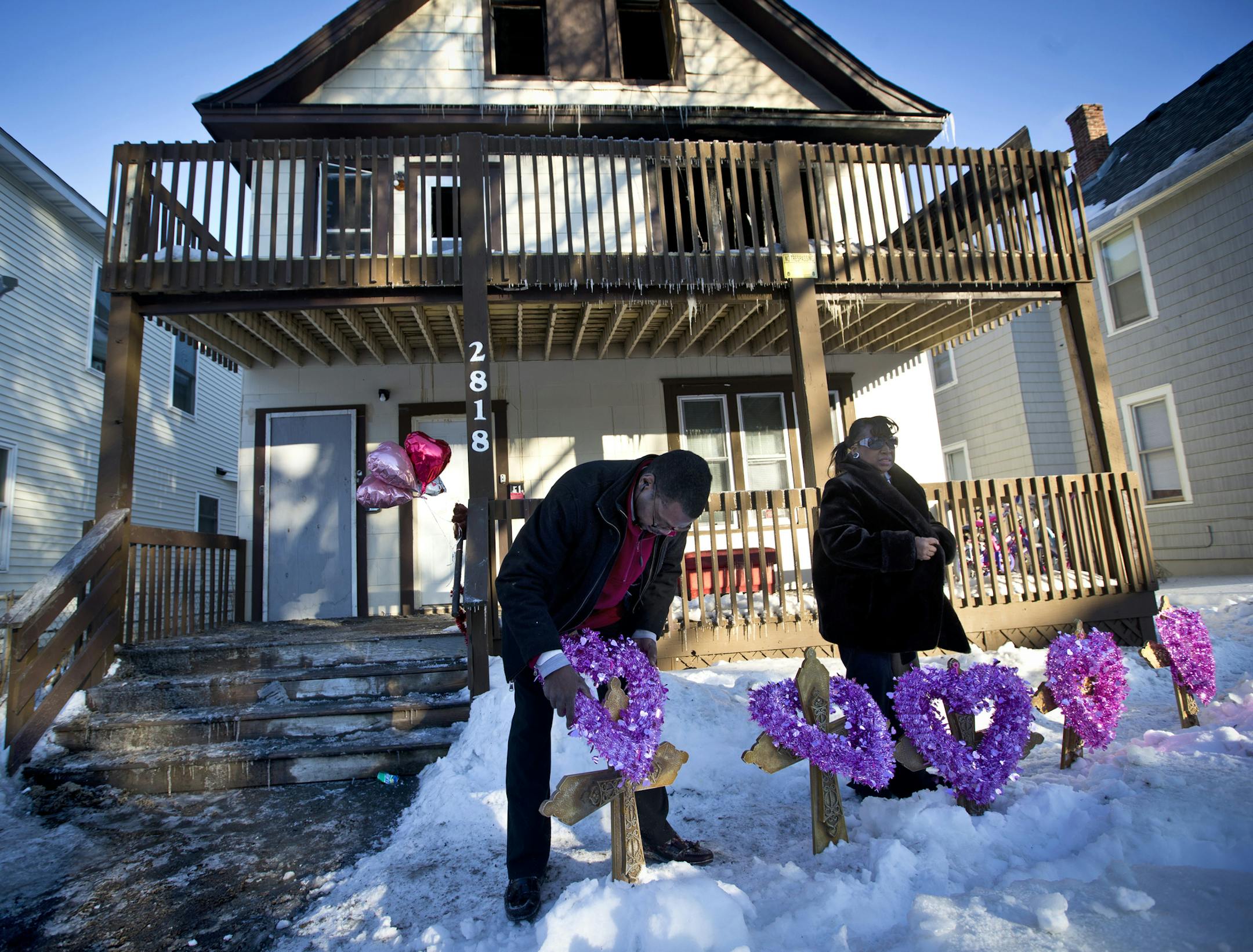 John Martin and Helen Williams put five crosses and wreaths in front of the home where five siblings were killed in an early morning house fire on Friday, February 14, 2014 in Minneapolis, Minn. John Martin was with the Minneapolis Federation of Teachers and Helen Williams runs a service to help people afford to bury their loved ones. ] (RENEE JONES SCHNEIDER reneejones@startribune.com) ORG XMIT: MIN1402141652052401