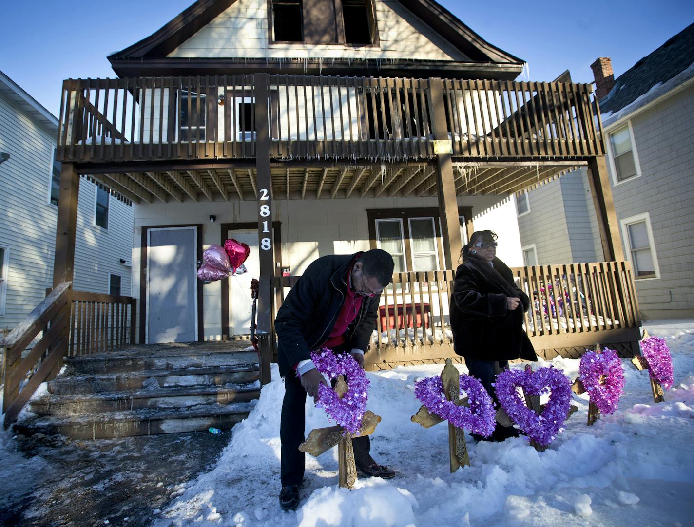 John Martin and Helen Williams put five crosses and wreaths in front of the home where five siblings were killed in an early morning house fire on Friday, February 14, 2014 in Minneapolis, Minn. John Martin was with the Minneapolis Federation of Teachers and Helen Williams runs a service to help people afford to bury their loved ones. ] (RENEE JONES SCHNEIDER reneejones@startribune.com) ORG XMIT: MIN1402141652052401