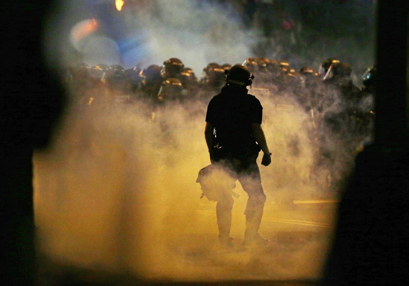 Police fire teargas as protestors converge on downtown following Tuesday's police shooting of Keith Lamont Scott in Charlotte, N.C., Wednesday, Sept. 21, 2016. Protesters have rushed police in riot gear at a downtown Charlotte hotel and officers have fired tear gas to disperse the crowd. At least one person was injured in the confrontation, though it wasn't immediately clear how. Firefighters rushed in to pull the man to a waiting ambulance.