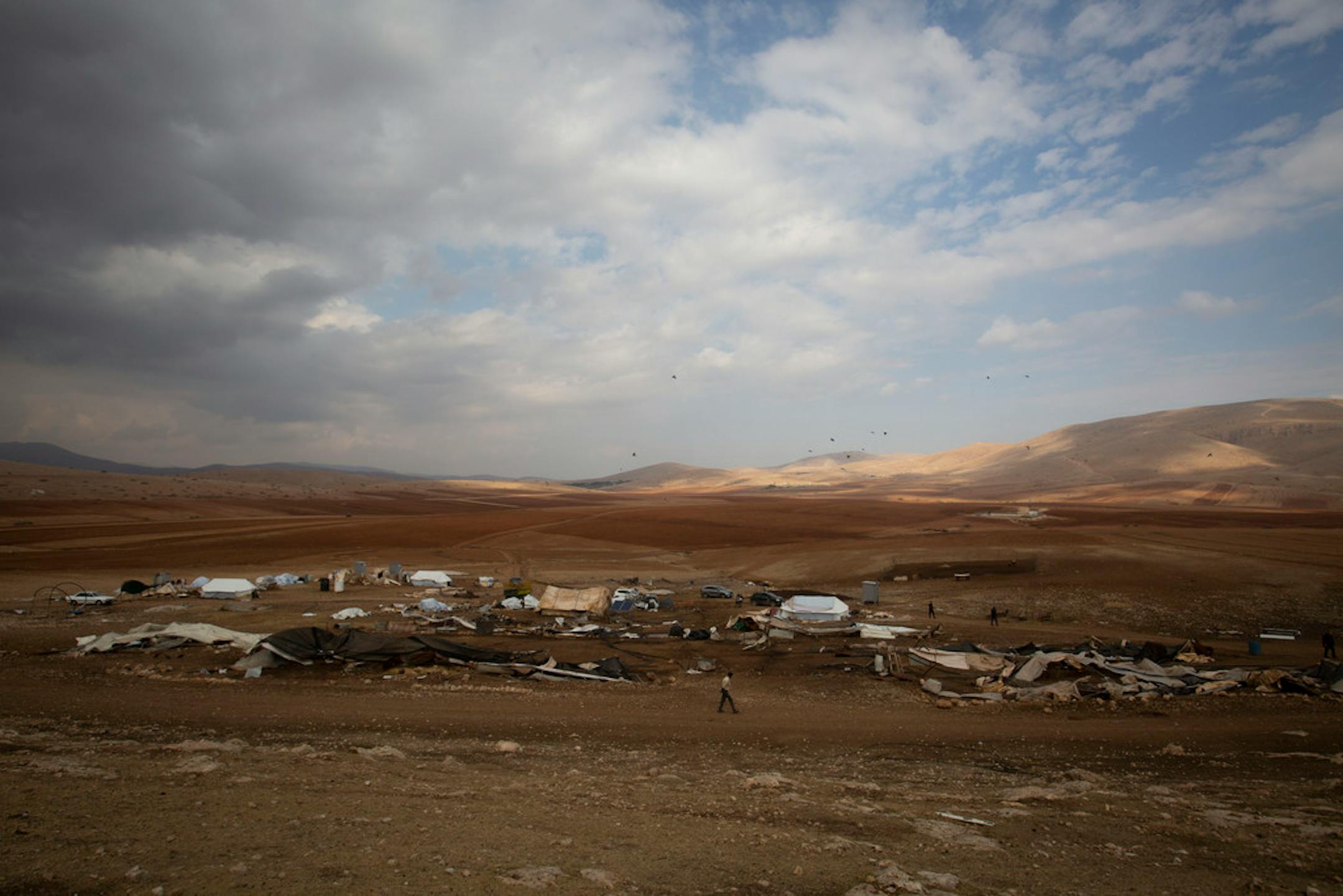 A Palestinian walks by destroyed tents in Khirbet Humsu in Jordan Valley in the West Bank, Friday, Nov. 6, 2020.