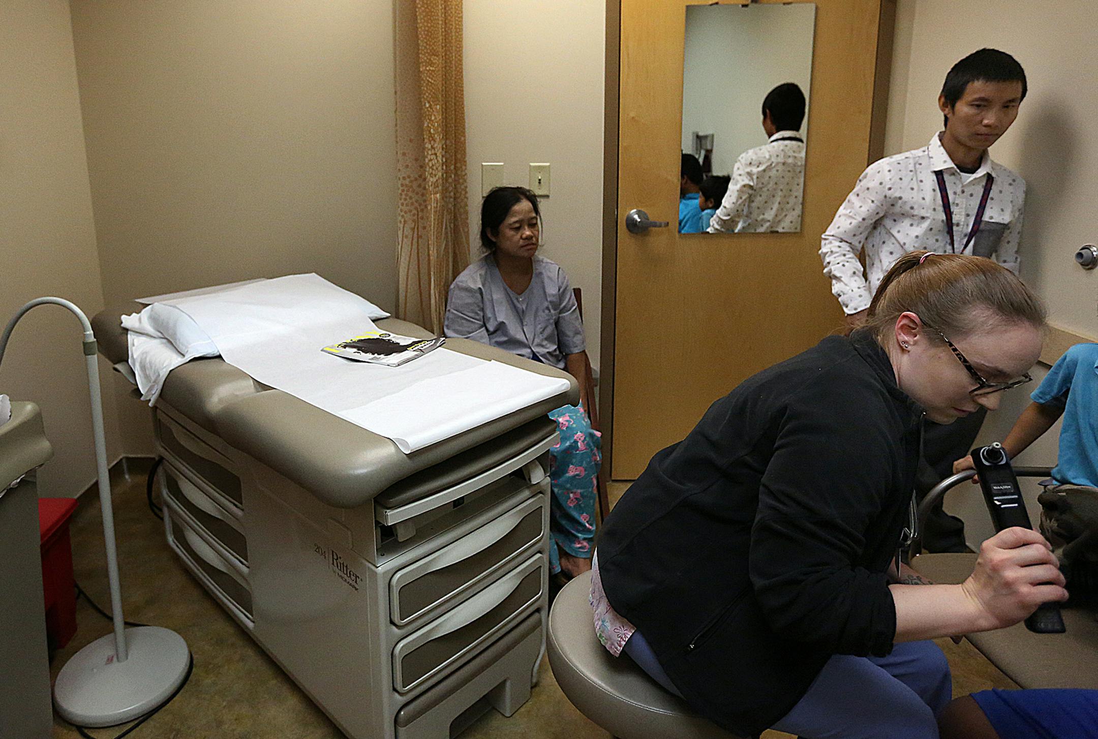 Interpreter Saw Minn, standing at right, worked with UCare enrollee Je Poe at a Maplewood clinic, where her children received checkups from Nicole Olson, right. The family is one of many members of the Karen immigrant community covered by UCare.
