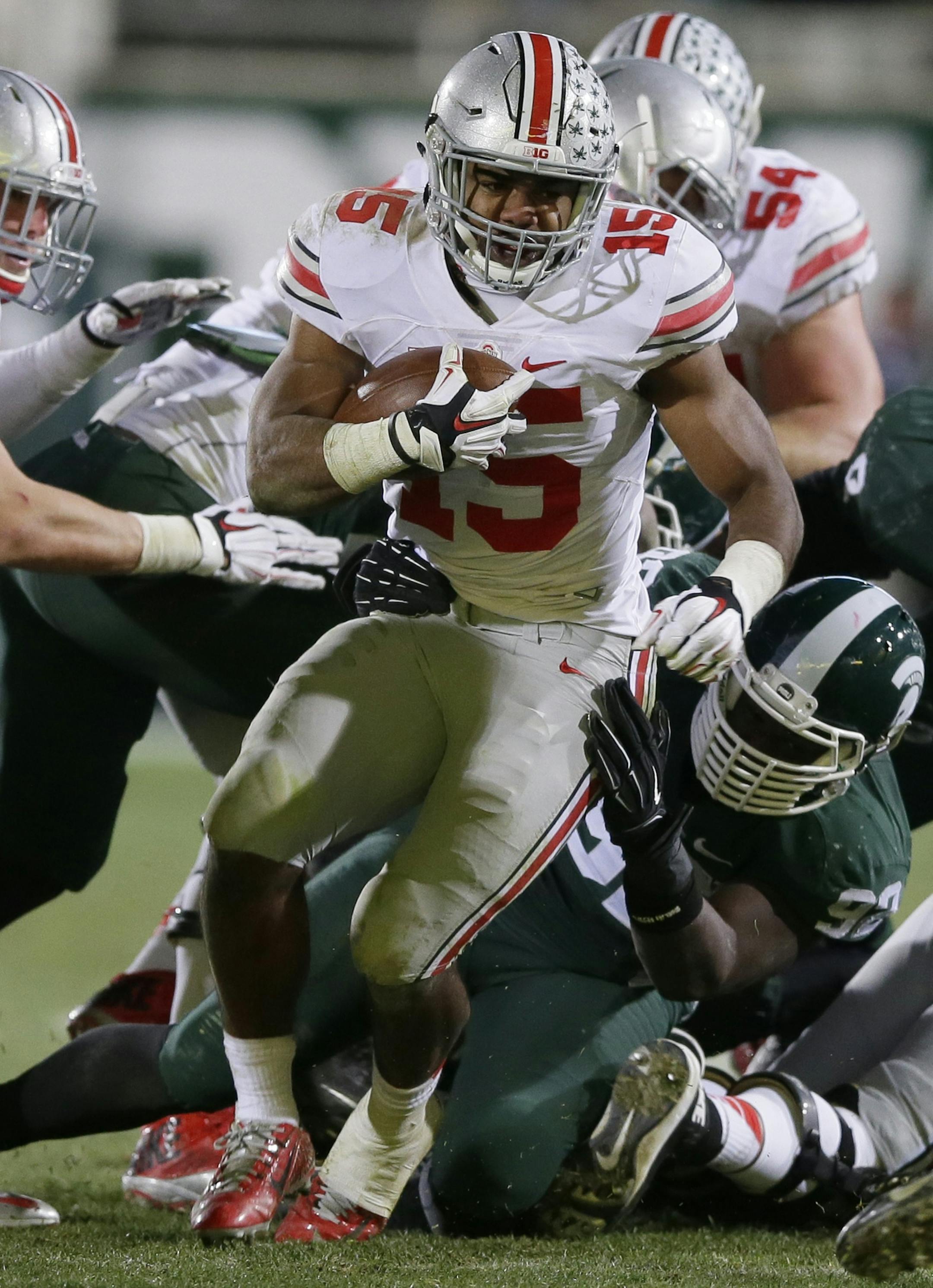 Ohio State running back Ezekiel Elliott (15) breaks through the Michigan State defense during the second half of an NCAA college football game in East Lansing, Mich., Saturday, Nov. 8, 2014. (AP Photo/Carlos Osorio) ORG XMIT: otkco121