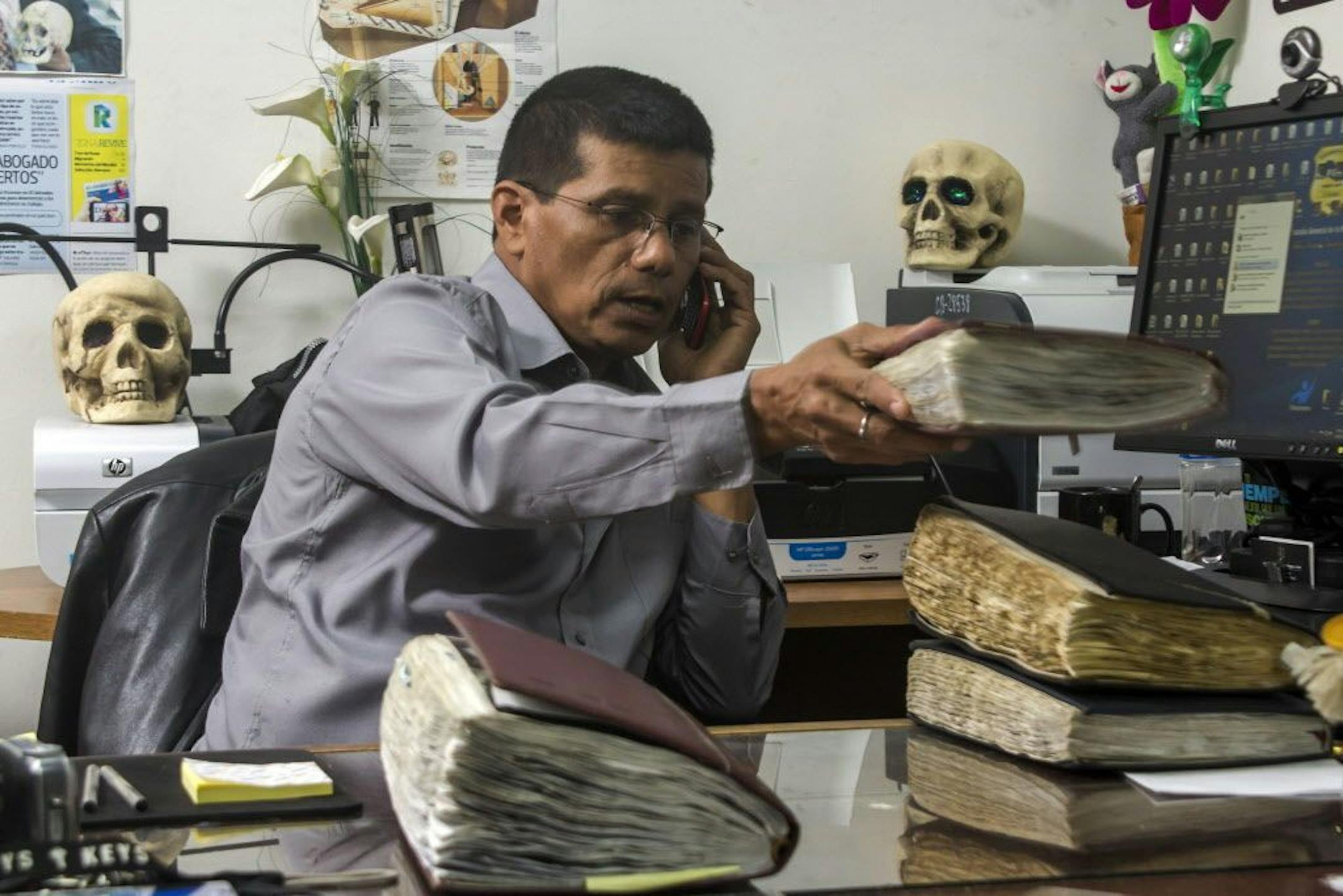 Criminologist Israel Ticas talks on the phone as he stacks his field notebooks, at his office in San Salvador, El Salvador.