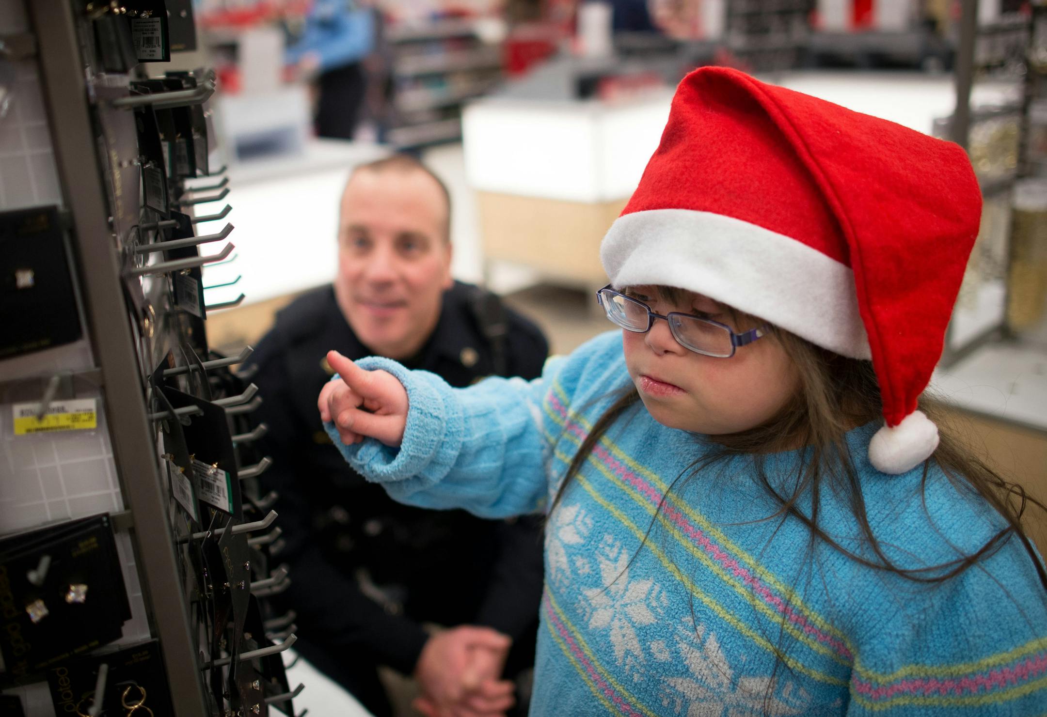 9-year-old Helaina Wilson looks for a pair of earrings for her mother with the help of Blaine Policeman Matt Carlson Tuesday night at Target. ] AARON LAVINSKY • aaron.lavinsky@startribune.com Anoka County cops and firefighters conduct their annual Heroes and Helpers event Tuesday, Dec. 2, 2014 at Target in Blaine. 48 children were given $100 gift cards to spend on themselves and their families while being escorted around target by first responders.
