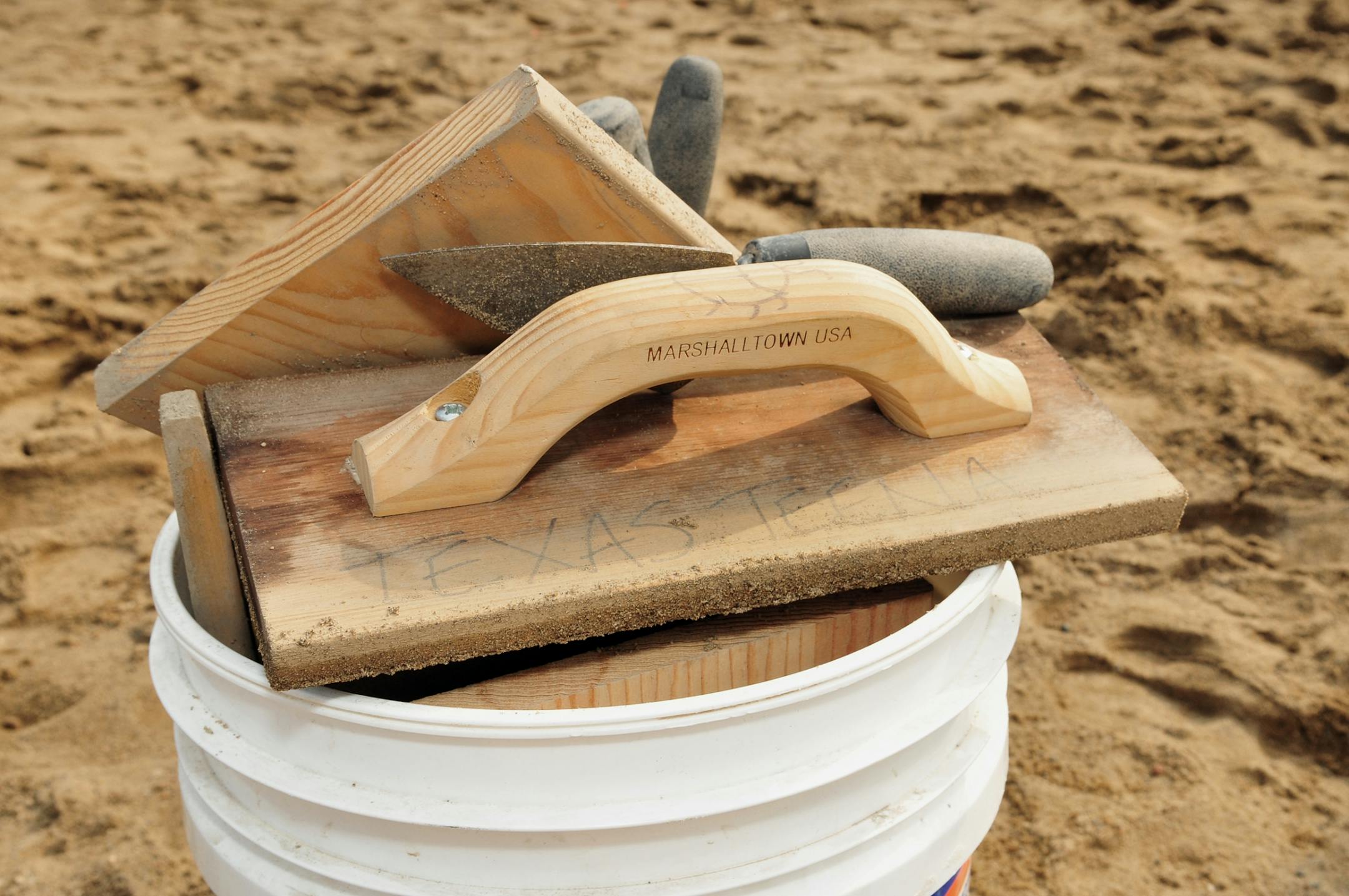 Erik Jorgenson and Kendall Bohn uses various tools to create their sand sculptures, including concrete floats for smoothing the sand. They also uses shovels, buckets, and sprayers, as well as trowels to carve details. .