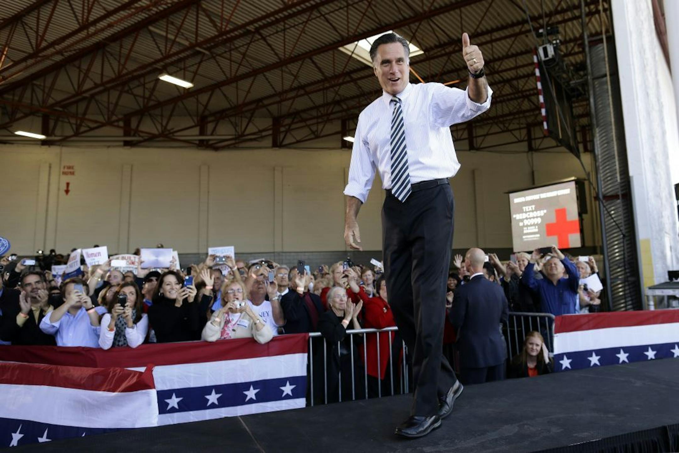 Republican presidential candidate, former Massachusetts Gov. Mitt Romney gives a thumbs up as he arrives at a campaign stop in Tampa, Fla., Wednesday, Oct. 31, 2012. At rear on screen is a number for Red Cross donations for victims of superstorm Sandy.