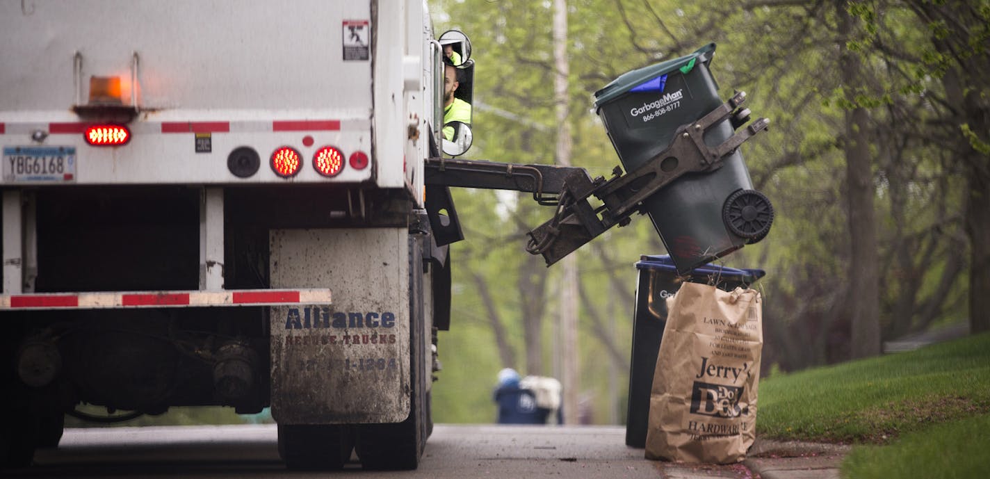 A GarbageMan worker empties containers onto the truck on trash pickup day in Bloomington between France Avenue and Normandale Boulevard on Thursday, May 7, 2015. ] LEILA NAVIDI leila.navidi@startribune.com / ORG XMIT: MIN1505071102290886