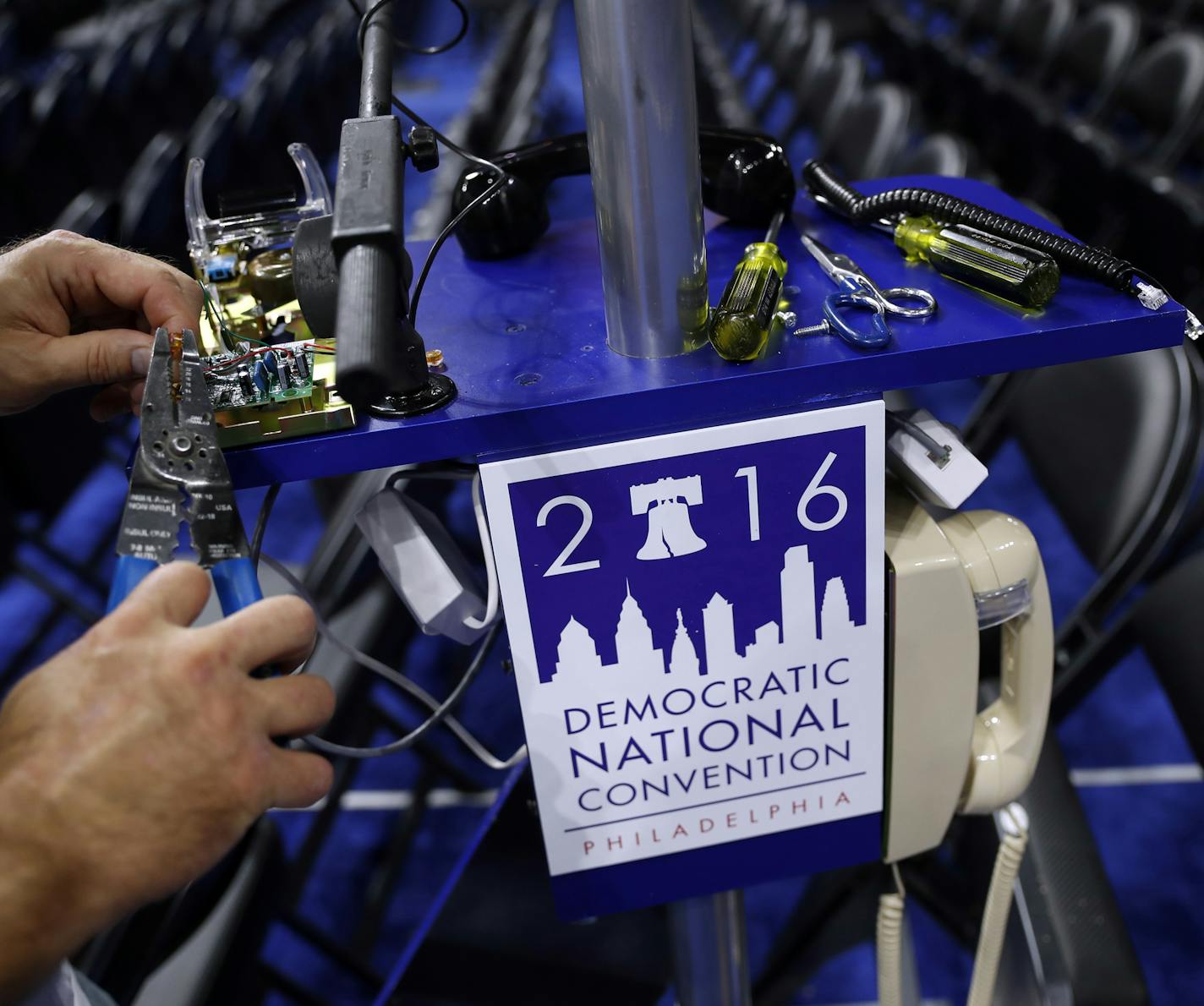 A worker wires a phone on the convention floor as setup continue before the 2016 Democratic Convention in Philadelphia, Saturday, July 23, 2016. (AP Photo/Carolyn Kaster)