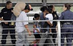Ever Castillo, left, and his family, immigrants from Honduras, are escorted back across the border by U.S. Customs and Border Patrol agents Thursday, 