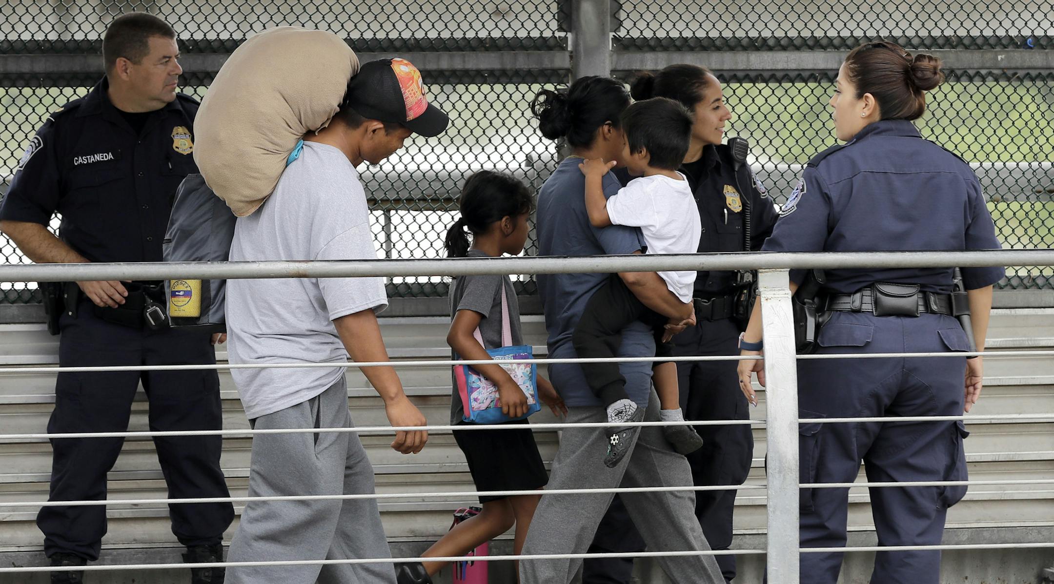 Ever Castillo, left, and his family, immigrants from Honduras, are escorted back across the border by U.S. Customs and Border Patrol agents Thursday, June 21, 2018, in Hildalgo, Texas. The parents were told they would be separated from their children and voluntarily crossed back to Mexico after trying to seek asylum in the United States. (AP Photo/David J. Phillip)
