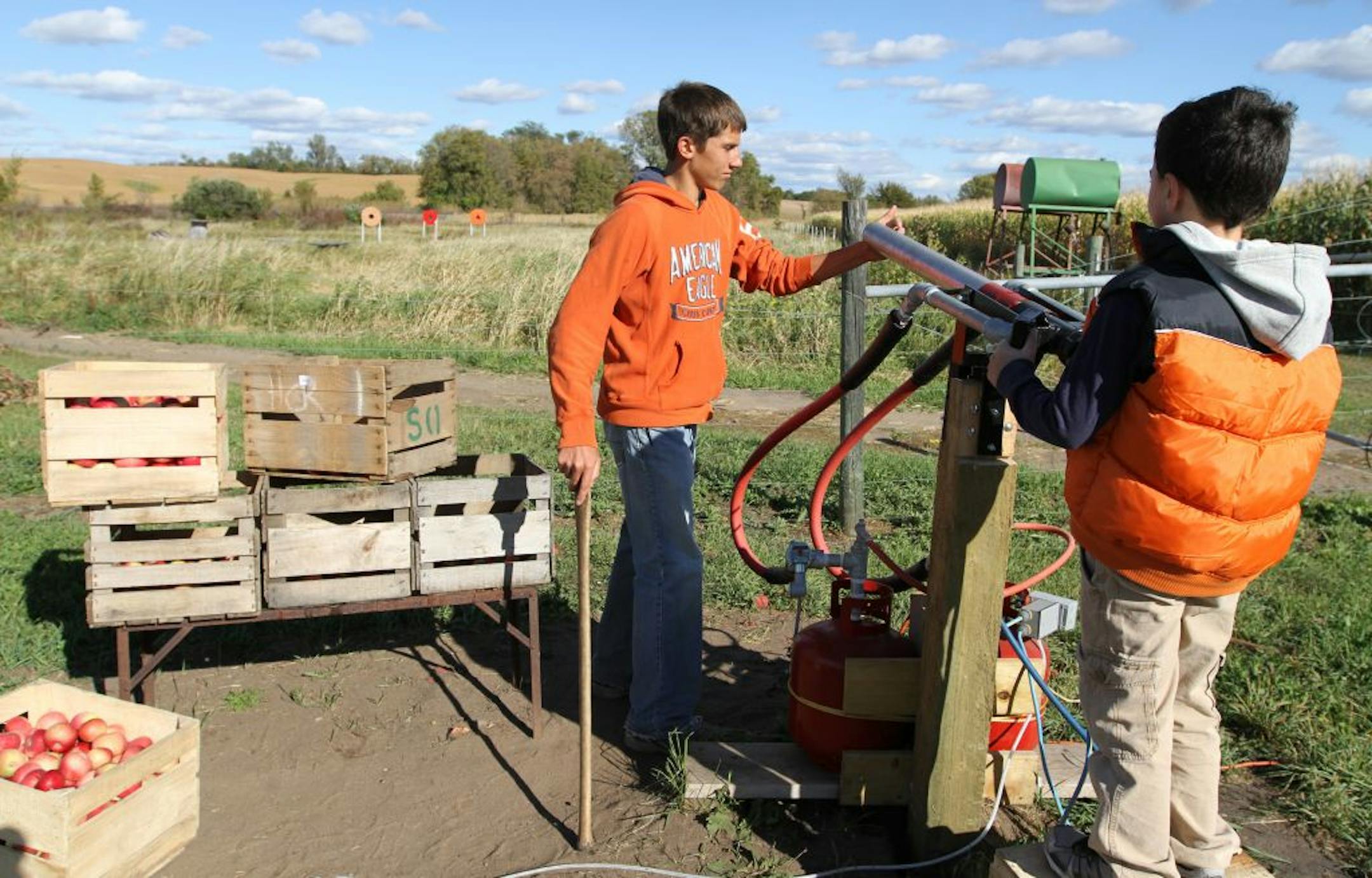 Spencer Muhonen, an employee of Apple Jack Orchards, loaded an apple into the orchard's apple canon Saturday. The orchard features activities for visitors beyond the traditional apple picking.