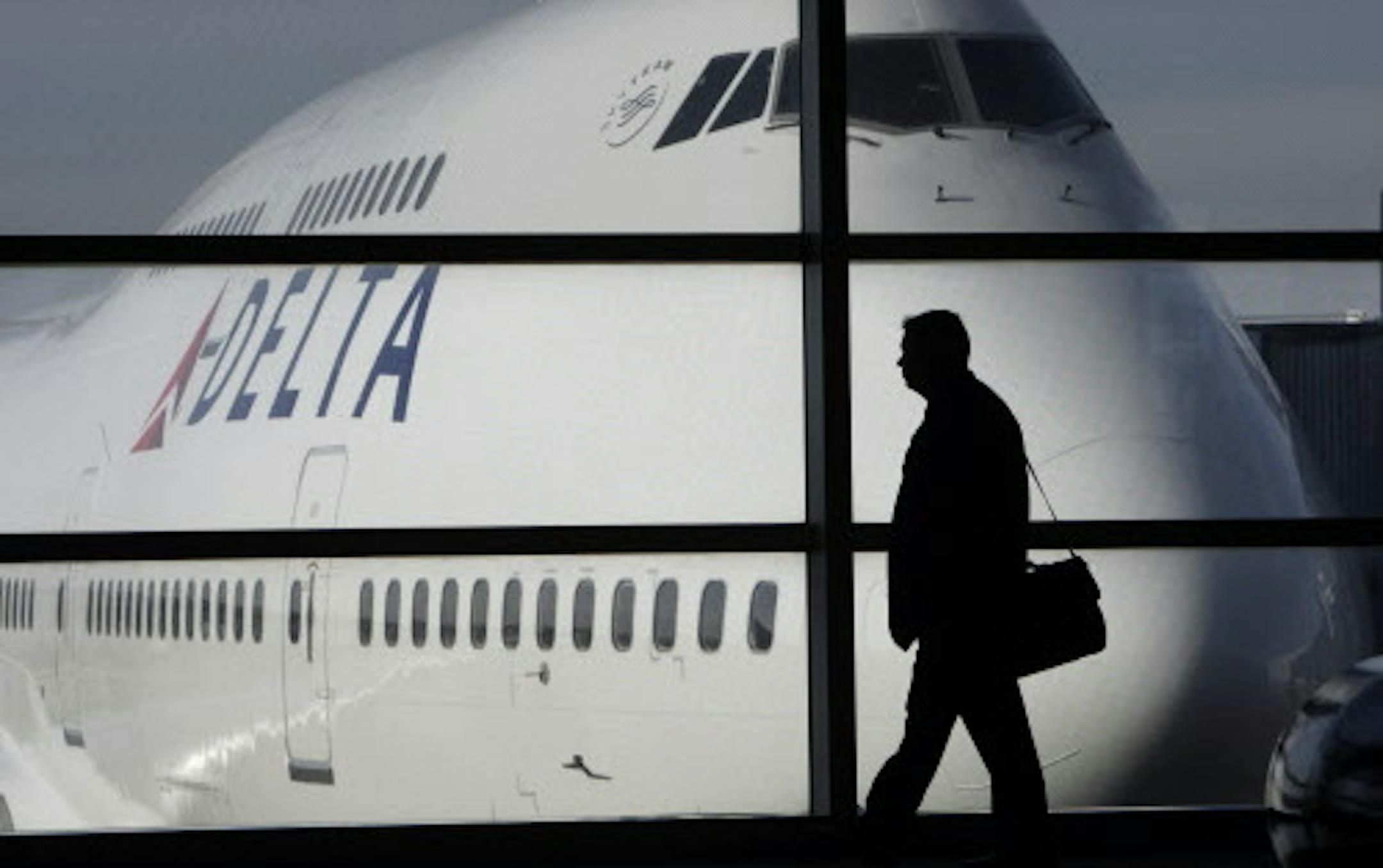 FILE - In this Jan. 21, 2010 file photo, a passenger walks past a Delta Airlines 747 aircraft in McNamara Terminal at Detroit Metropolitan Wayne County Airport in Romulus, Mich. Fares are higher, demand is up and the airlines have established a steady revenue stream from add-on fees for baggage, pillows and food. (AP Photo/Paul Sancya, file) ORG XMIT: MIN2012090615575792