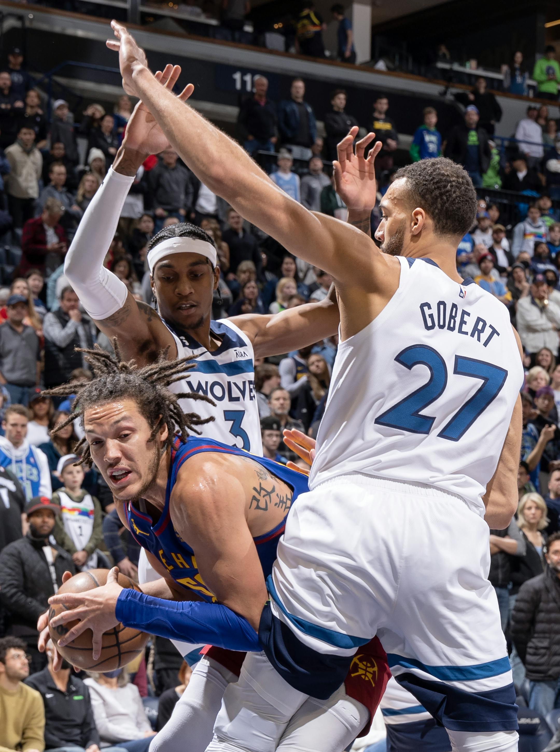 Aaron Gordon (50) of the Denver Nuggets is defended by Jaden McDaniels (3) and Rudy Gobert (27) of the Minnesota Timberwolves in the fourth quarter.