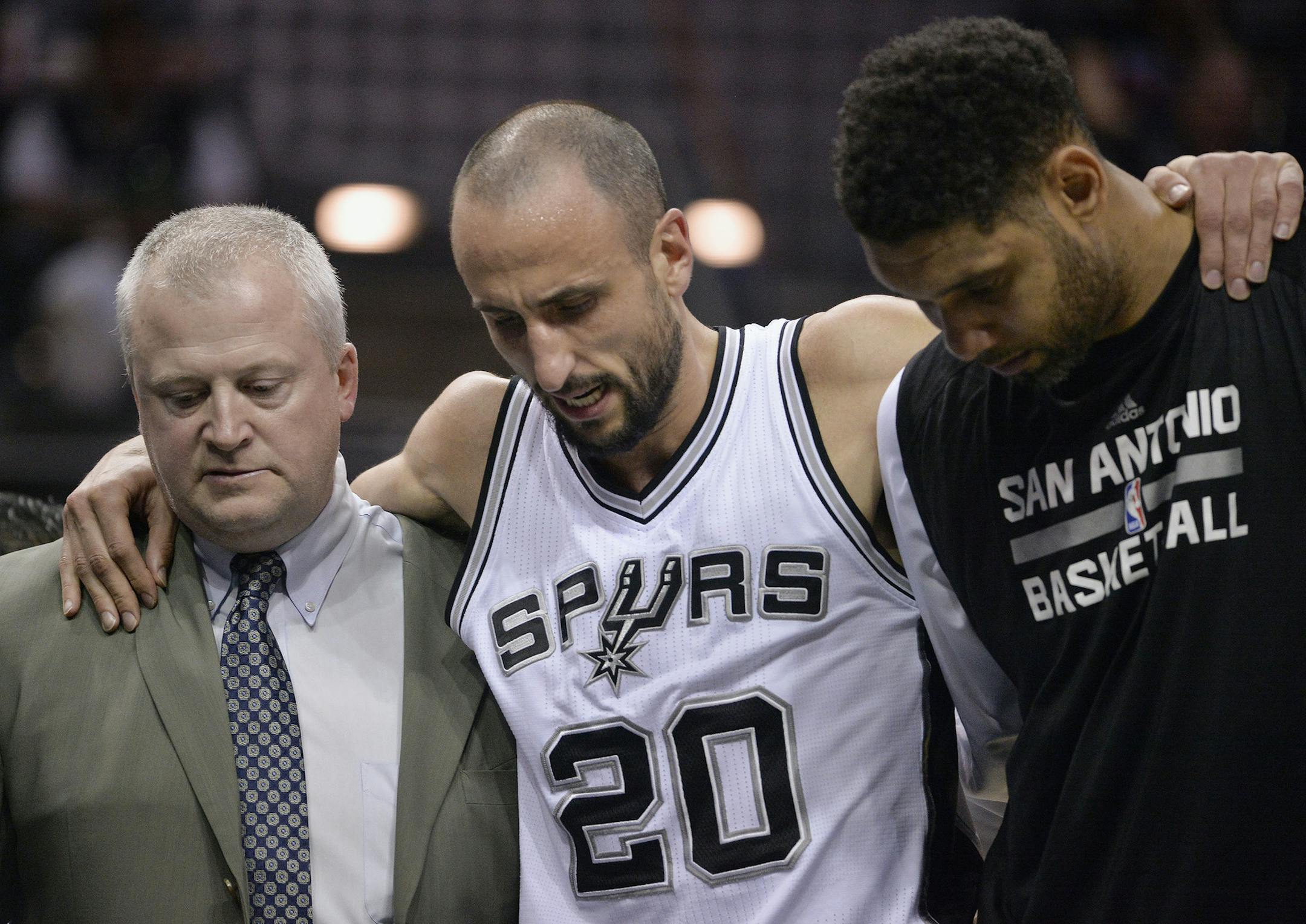 San Antonio Spurs guard Manu Ginobili, center, of Argentina, is helped off the court by Spurs forward Tim Duncan, right, and Spurs trainer Will Sevening, after injuring his ankle during the third quarter of an NBA basketball game against the Minnesota Timberwolves, Sunday, March 15, 2015, in San Antonio. San Antonio won 123-97. (AP Photo/Darren Abate)
