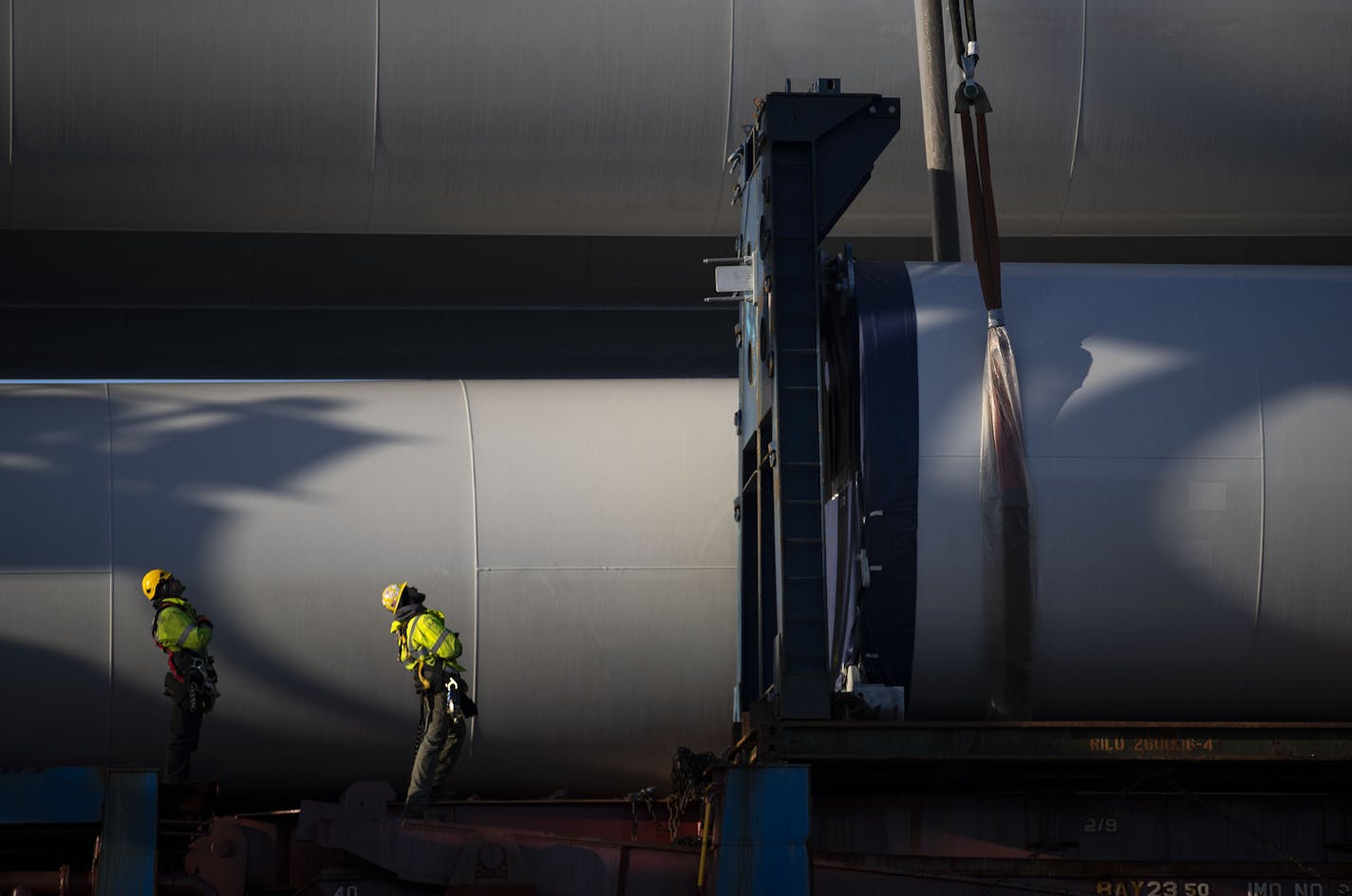 Workers watched and guided crane operators as they moved a section of a wind turbine tower off the BBC Xingang and onto a flatbed truck.