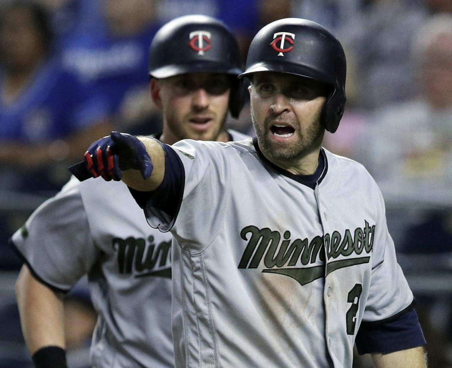 Minnesota Twins' Brian Dozier points to the third base coach after scoring on a double by teammate Eddie Rosario during the eighth inning of a baseball game against the Kansas City Royals at Kauffman Stadium in Kansas City, Mo., Monday, May 28, 2018. (AP Photo/Orlin Wagner)