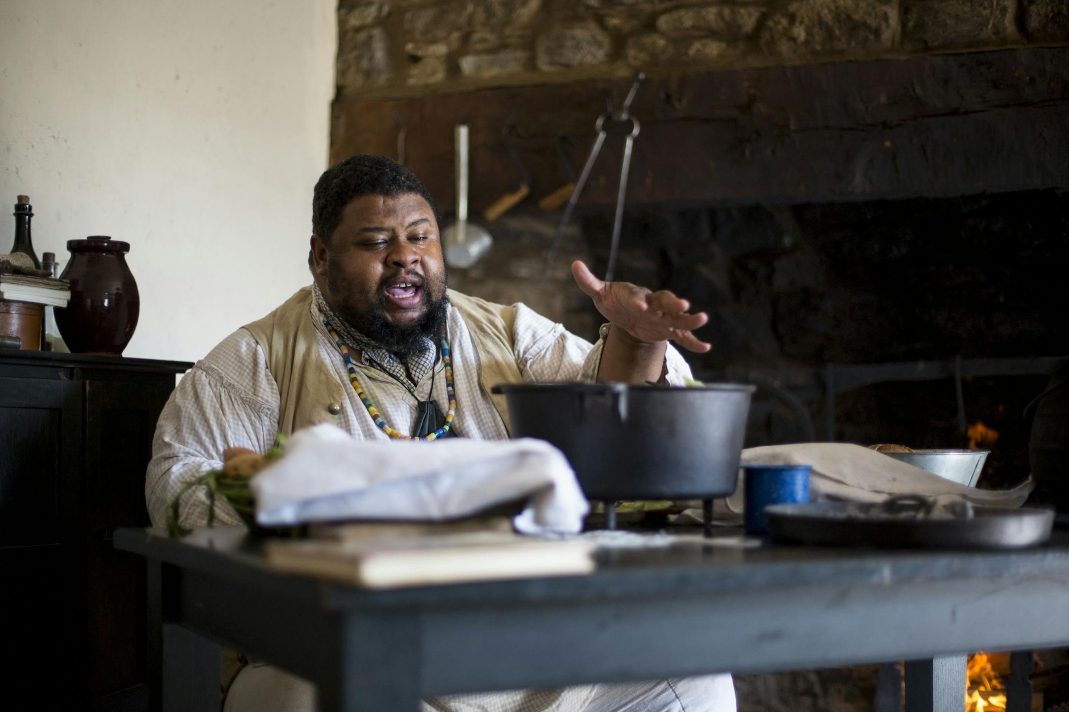 Michael Twitty tells the crowd how he will encase the chicken in cabbage leaves before putting it over the coals.