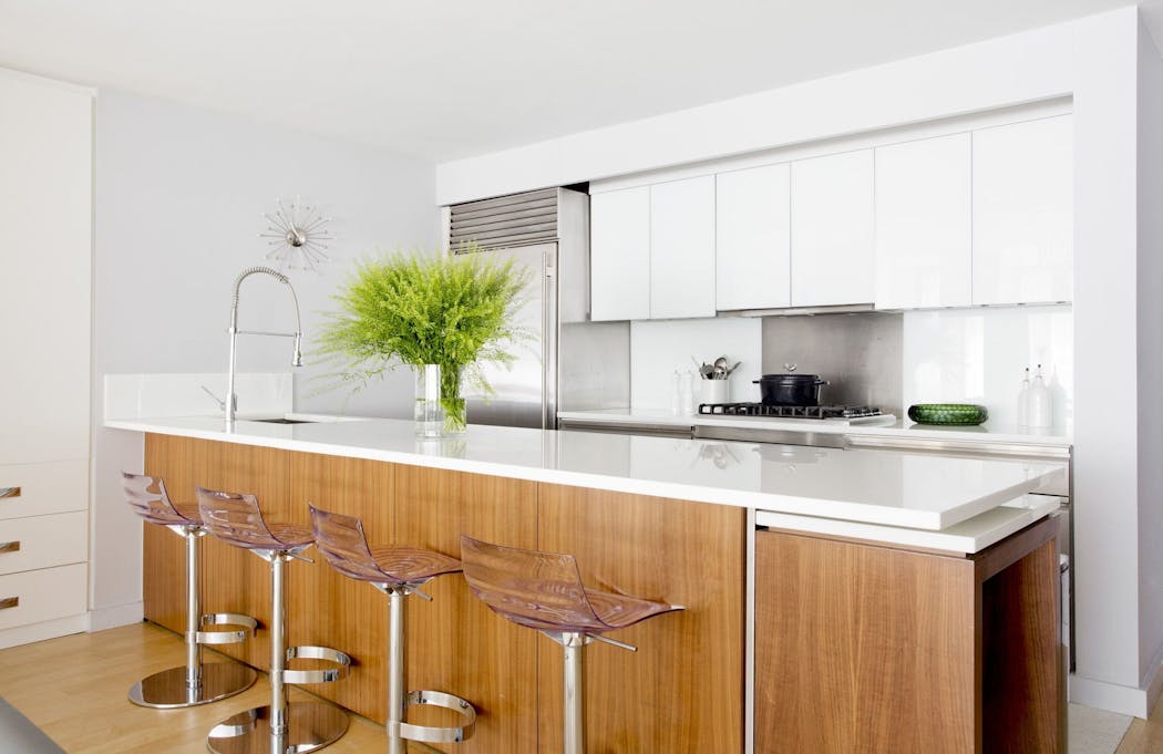 White quartz, which has surpassed stone in popularity, covers the countertops and backsplash in this modern open kitchen.