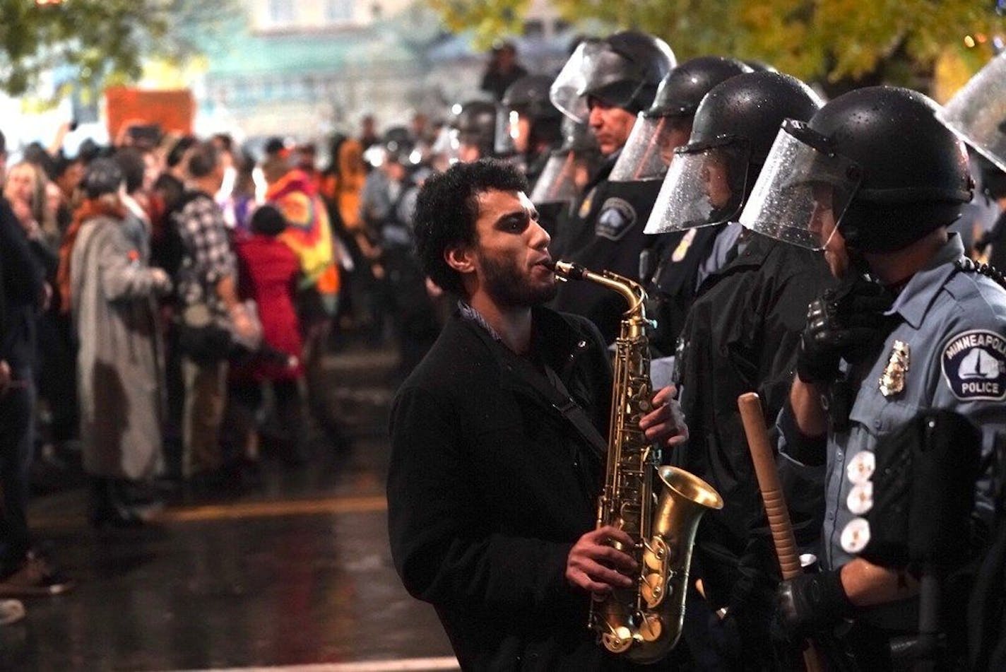 Matthew Trice played saxophone in front of a police line atTarget Center on Oct. 10, 2019. Protesters demonstrated outside as President Donald held a reelection rally inside.