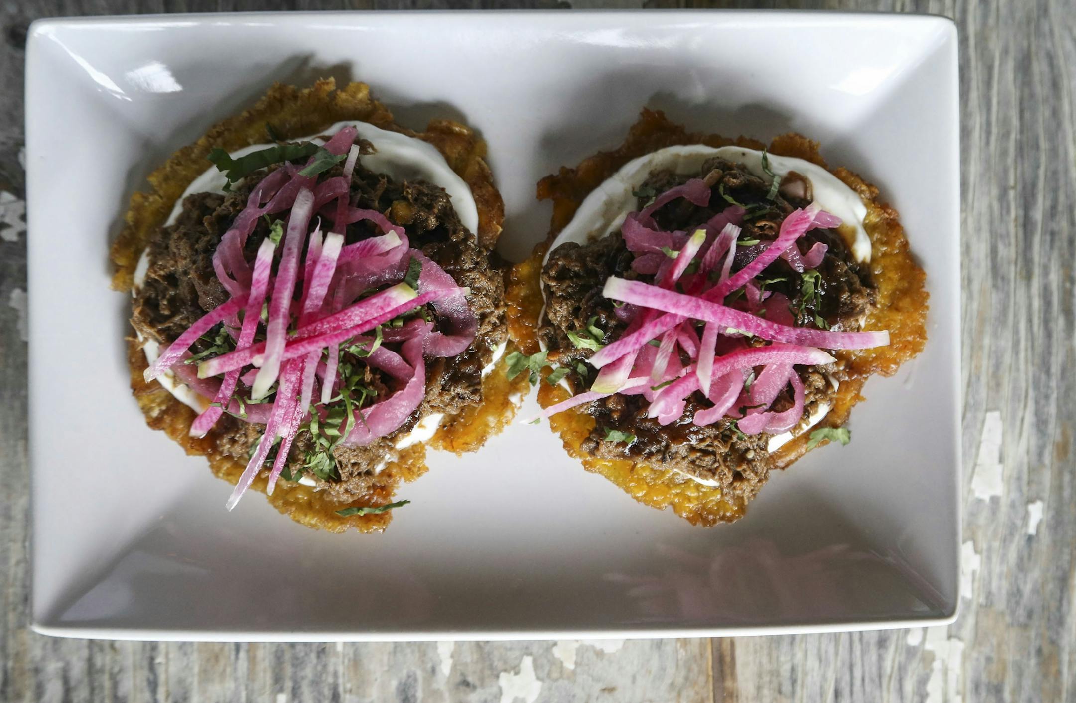 Hola Arepa, one of the city's great food trucks and now a restaurant, and plantain tostadas with braised beef, citrus crema, tamarind sauce, watermelon radish and pickled onion Friday, Sept. 12, 2014, in Minneapolis, MN.
