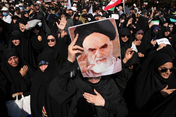 A pro-government demonstrator holds a poster of the late Iranian revolutionary founder Ayatollah Khomeini while attending a rally after the Friday pra