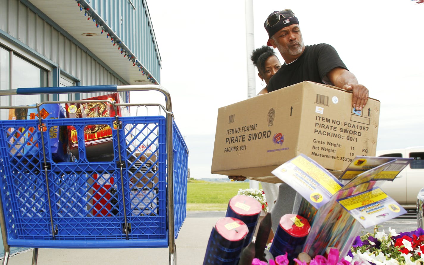 In this photo taken Thursday, June 23, 2016, Anthony Rodgers of Wauwatosa, Wis., loads a box of fireworks with his wife Kimberly into their car outside of Uncle Sam's Fireworks in Wayne, Wis. The Rodgers bought about 200 different colored fireworks. (John Ehlke/West Bend Daily News via AP) MANDATORY CREDIT