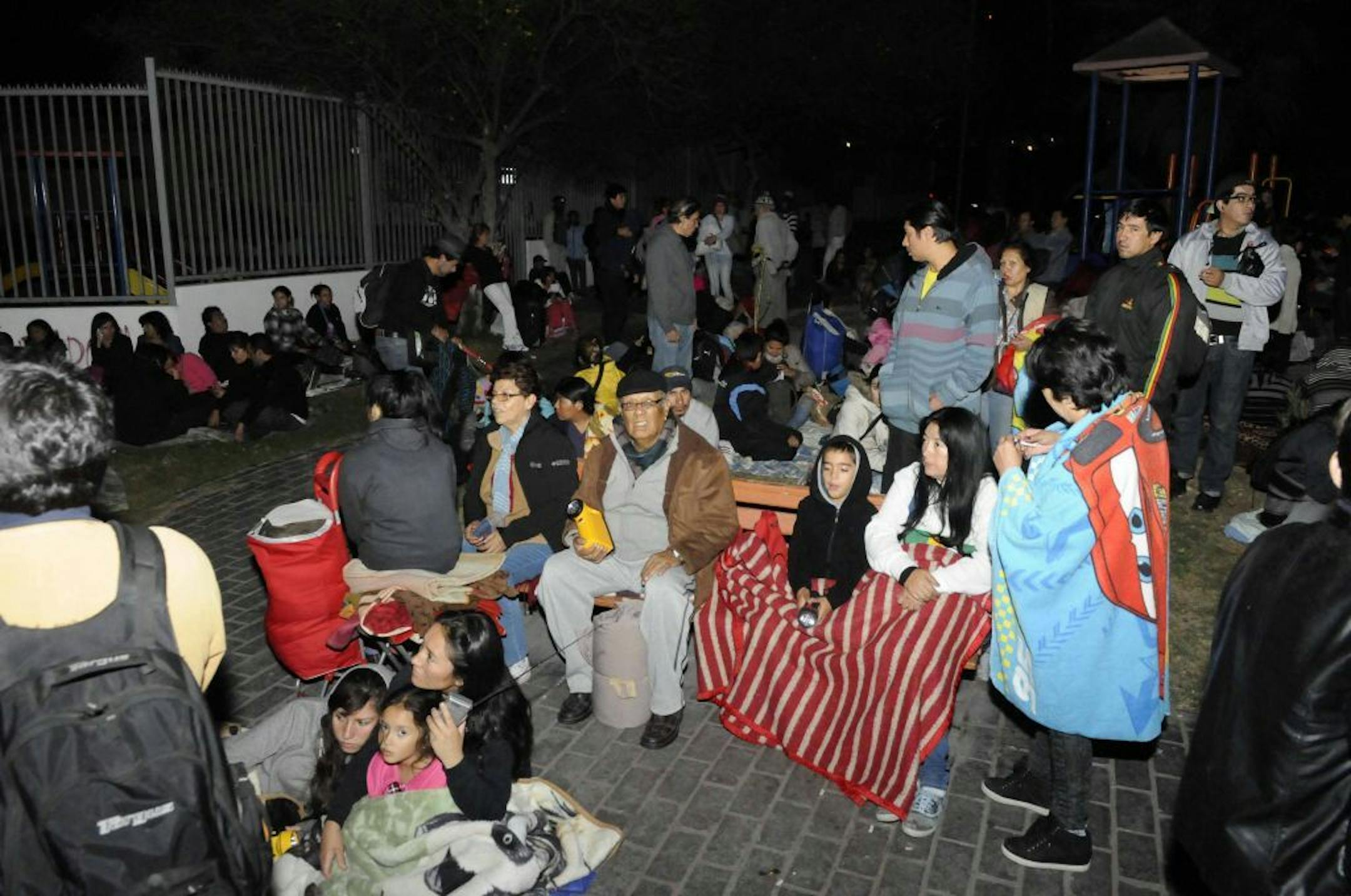 People sit outside as they evacuate their homes after a strong aftershock in Iquique, Chile, early Thursday, April 3, 2014.