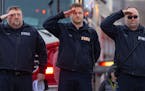 Firefighters saluted a planned processional for Firefighter/Paramedic Adam Finseth who was killed on Sunday in a shooting in Burnsville, along with tw