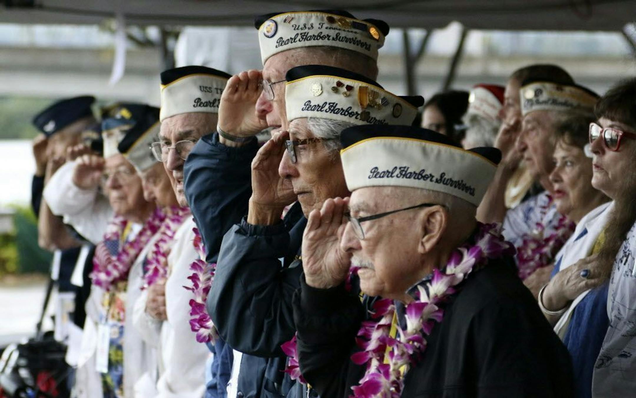 Pearl Harbor survivors salute during the National Anthem at a ceremony in Pearl Harbor, Hawaii on Friday, Dec. 7, 2018 marking the 77th anniversary of the Japanese attack. The Navy and National Park Service jointly hosted the remembrance ceremony at a grassy site overlooking the water and the USS Arizona Memorial.