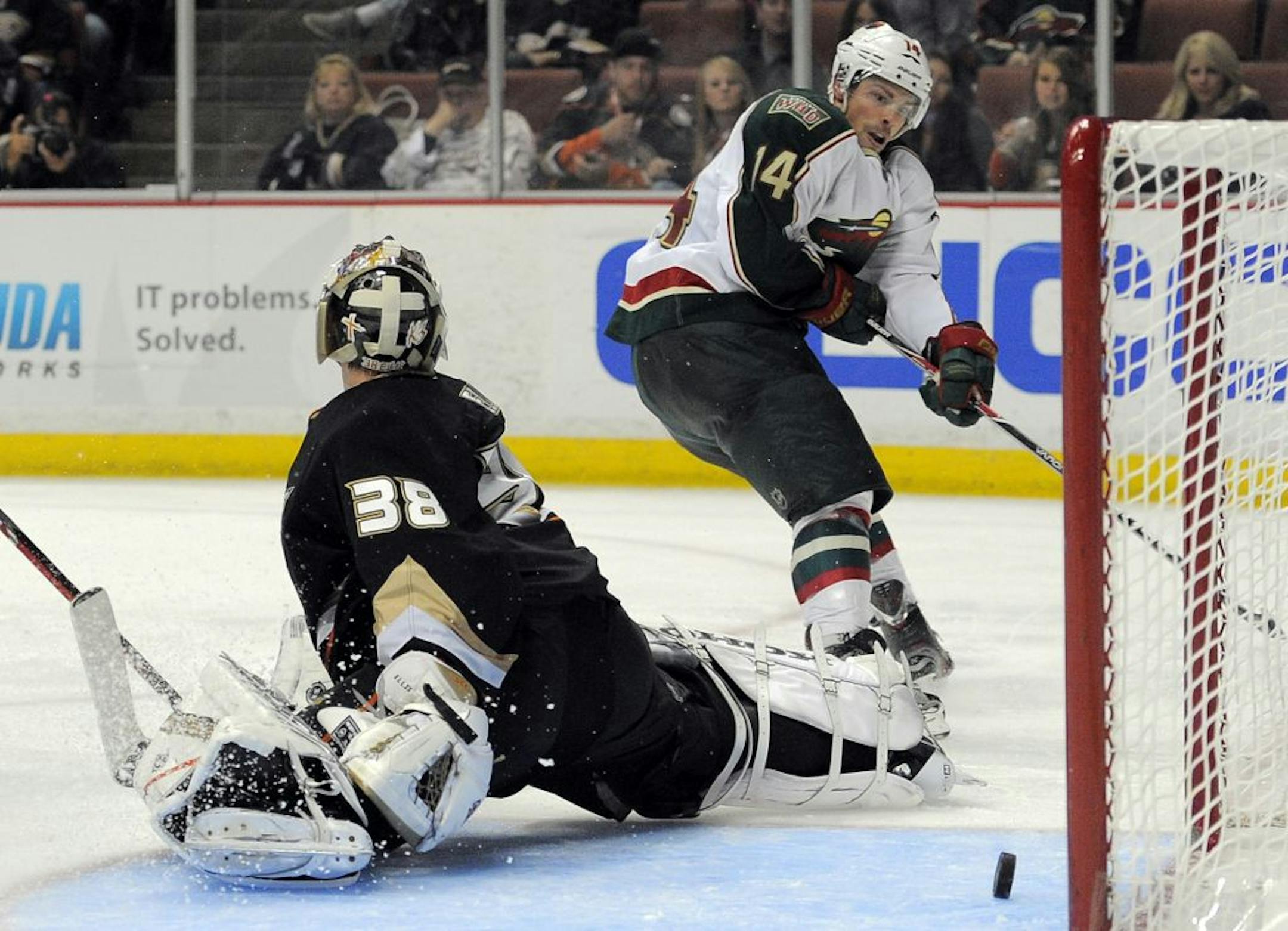 Minnesota Wild left wing Darroll Powe, right, makes a shot attempt that goes through the crease as Anaheim Ducks goalie Dan Ellis defends during the third period of their NHL hockey game, Sunday, Nov. 13, 2011, in Anaheim, Calif. The Wild won 3-2.